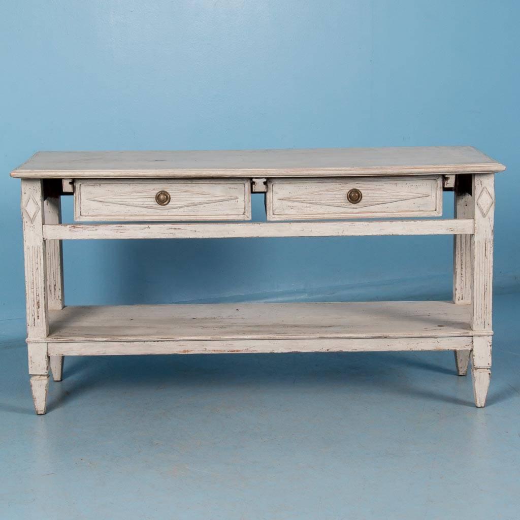 This antique Gustavian table with a pair of drawers and open shelving below is painted on all four sides. As it is 