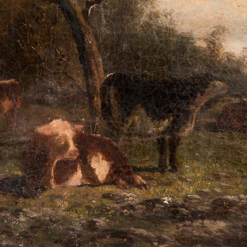 Antique 19th century original English oil painting on canvas of a landscape with a herd of cows in the foreground and a village in the background. The painting is dated and signed illegibly in the lower left and mounted in a giltwood and plaster