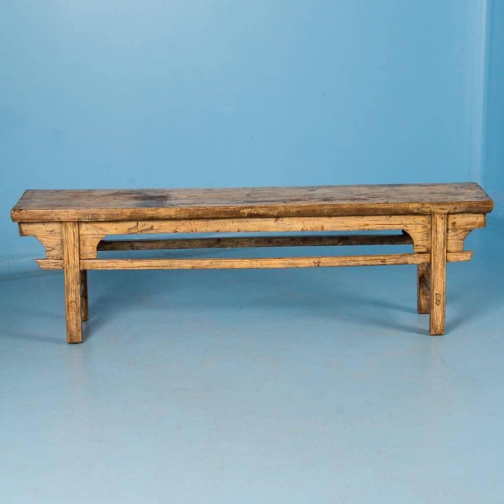 Antique hardwood bench from China, circa 1850, retaining most of its pale yellow paint, and sealed with a satin wax finish. The 2