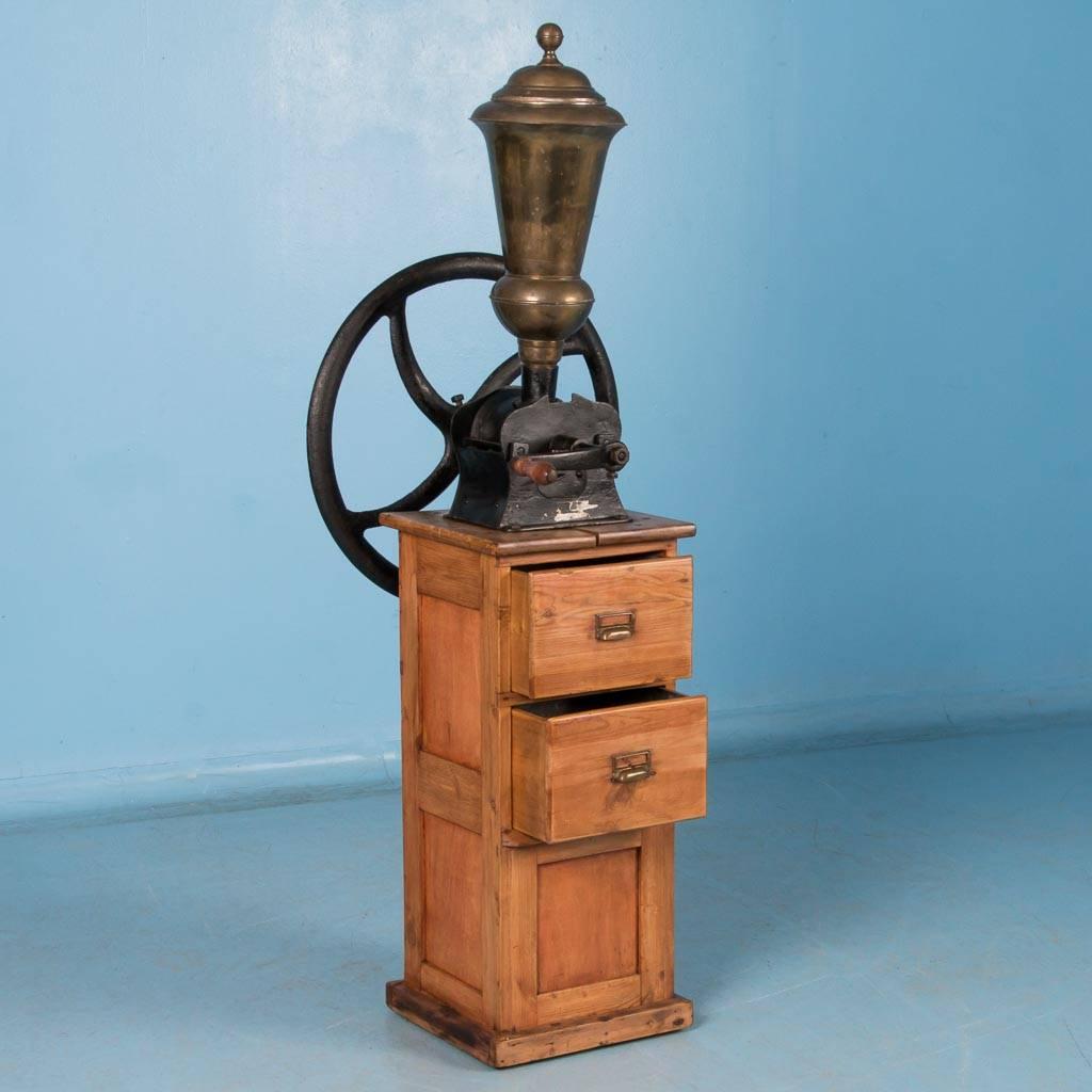 Antique Danish cast iron hand operated coffee grinder, circa 1900-1920. This commercial floor model features an all wooden base with two tin lined collection drawers, brass hopper and a cast iron grinding mechanism. Please take a moment to enlarge