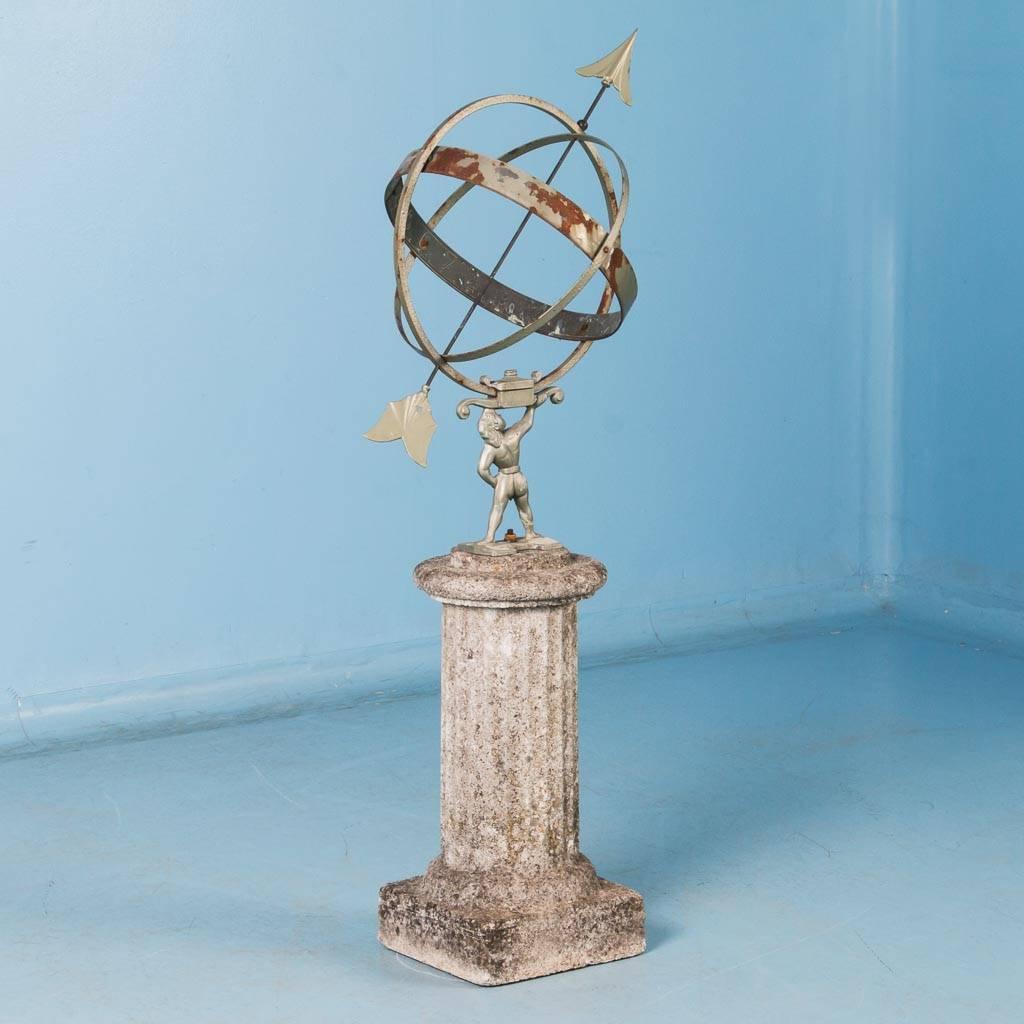 Antique garden ornament from Denmark, circa 1920-1940, known as a Sun Clock or Armillary, with a cast metal figure holding spherical rings and mounted on a stone base (like Atlas holding up the world). The metal of this sun clock has remnants of