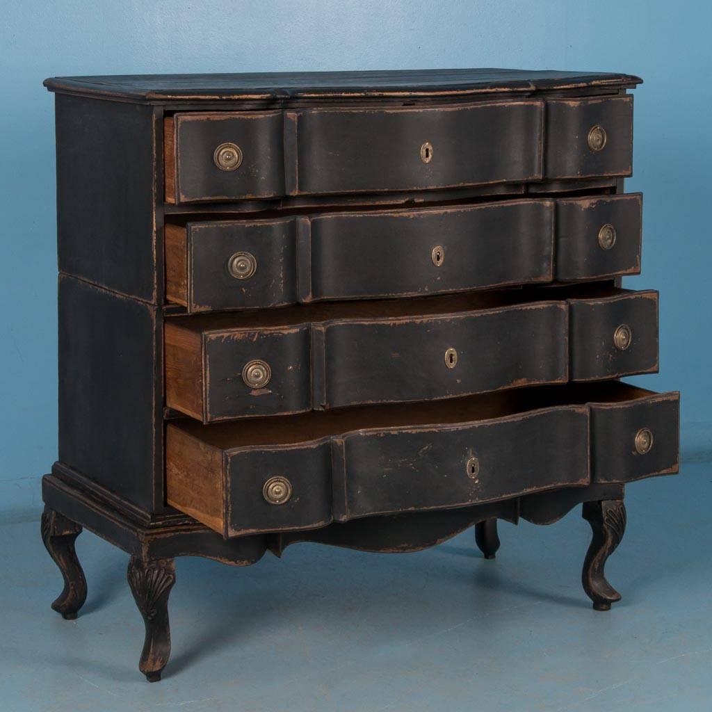 This antique Baroque oak chest of drawers from Denmark circa 1760-1780, features a serpantine front, brass hardware and an exceptional matte black painted finish. Made in three parts, the upper case with two drawers rests on the base with squared