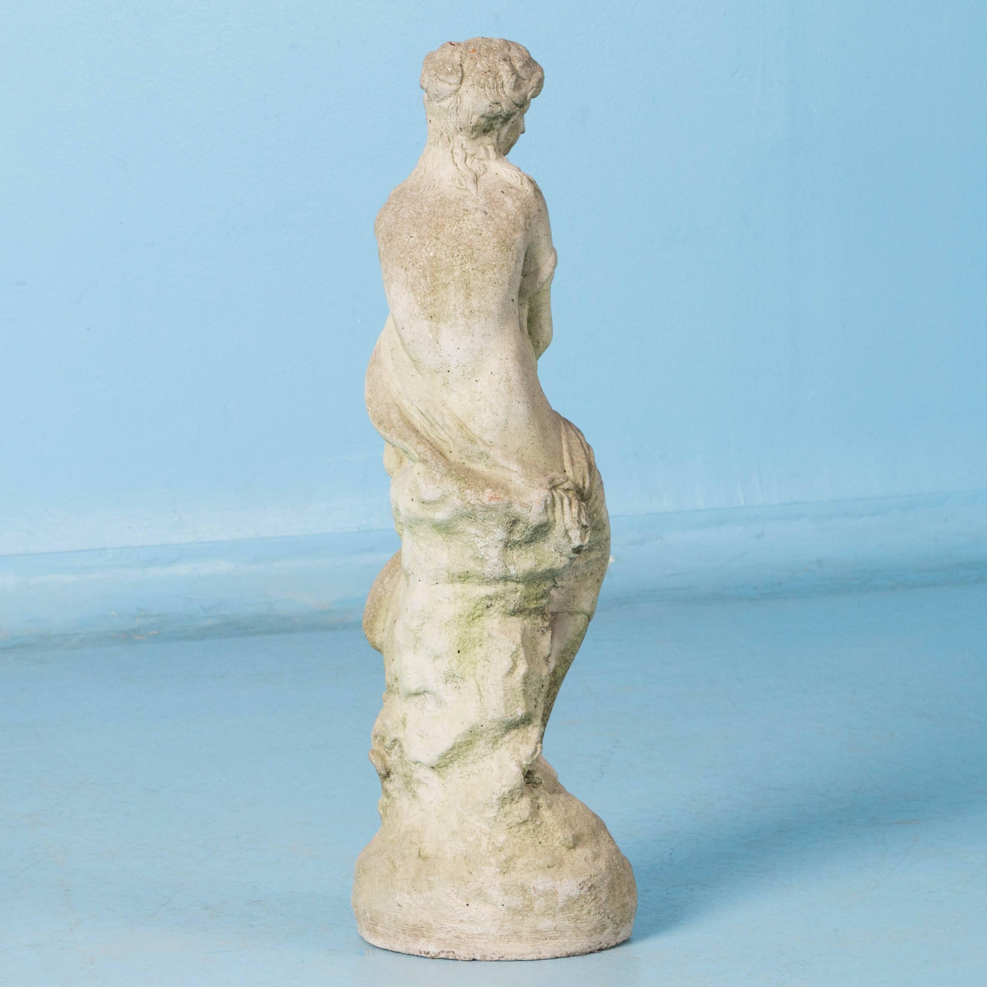 Small cast concrete figure of a robed woman, circa 1920-1940, with a very smooth weathered surface due to years of being outdoors. Having been exposed to the elements, it has an aged patina of light and dark grays with patches of light green most