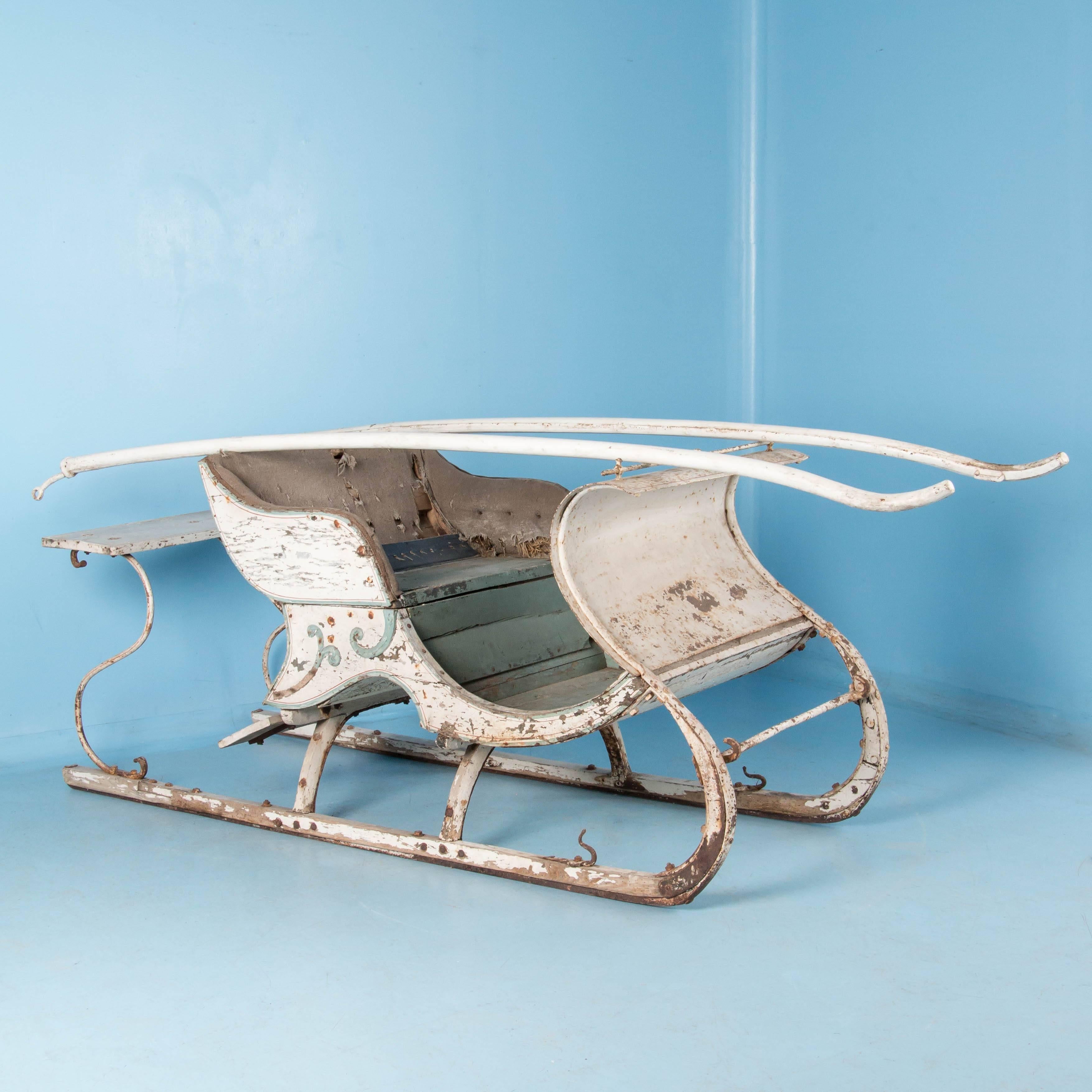 Antique white horse drawn sleigh from Sweden in as found condition. The sleigh comes with the original long wooden traces or tugs that connect to the curved hooks located at the front of each runner, as well as remnants of the original upholstered