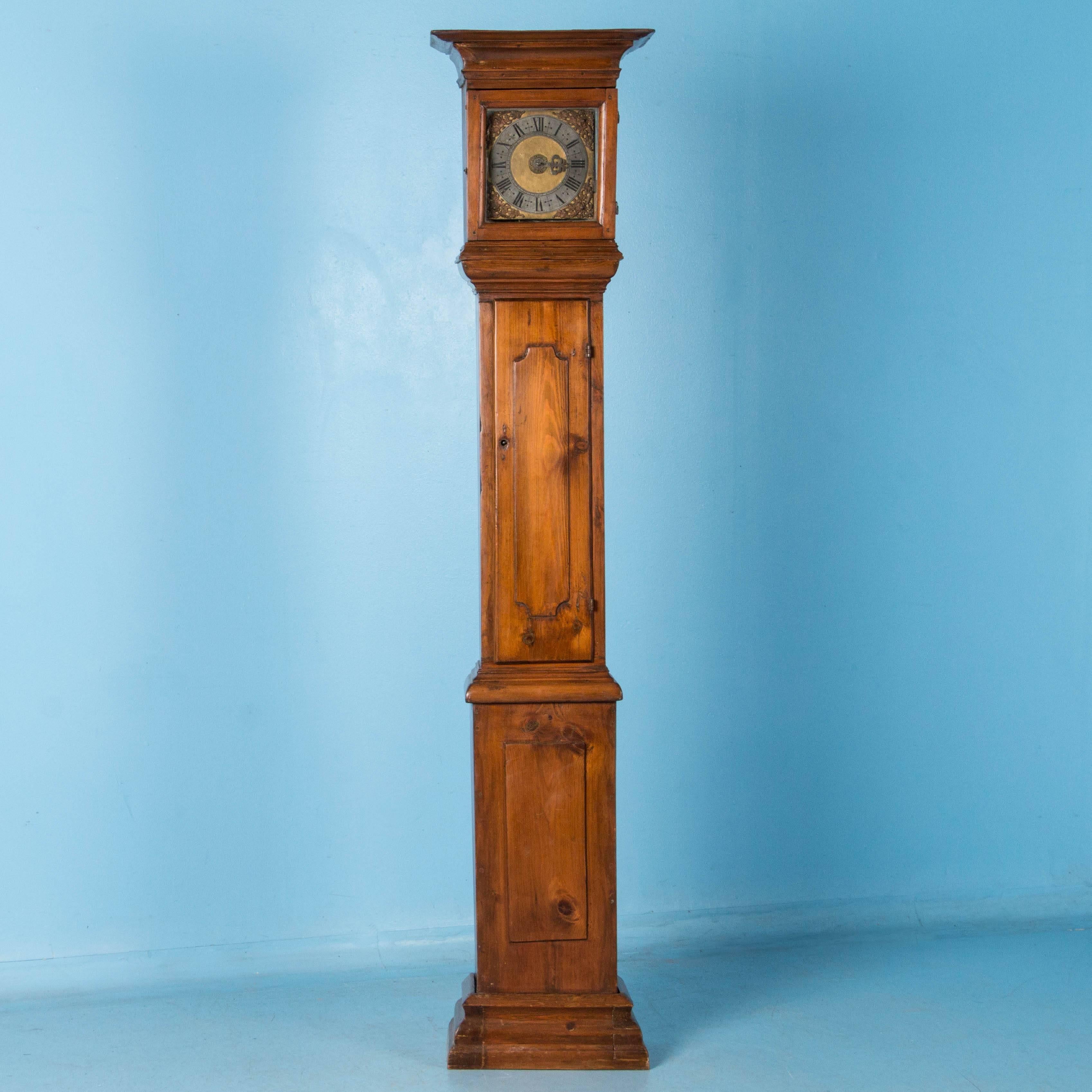 Simple yet elegant, this tall narrow Swedish grandfather clock features a square face in gold, silver and brass with Roman numerals. A satin wax finish has been applied and enhances the patina of the pine.

 Prior to shipping, the original