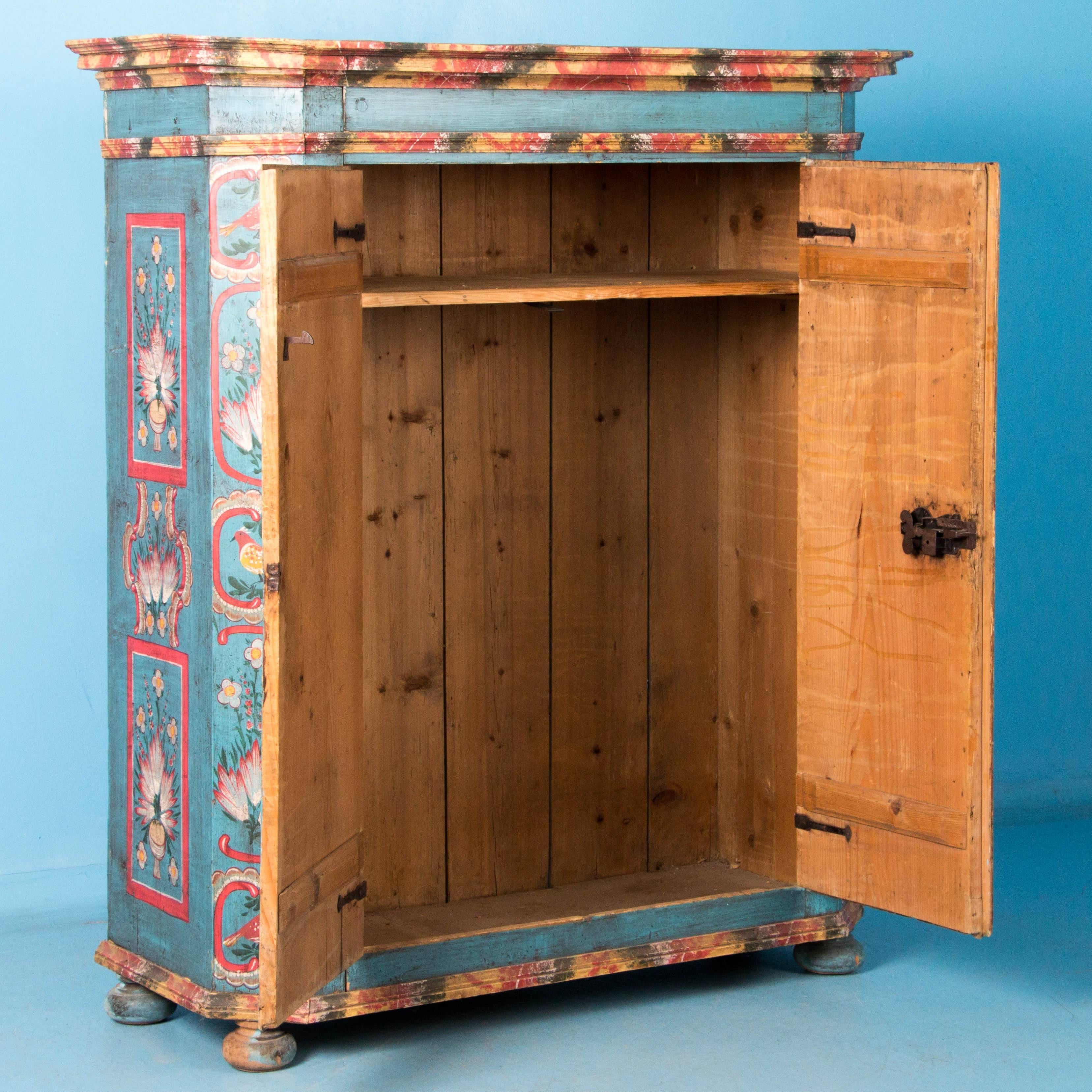 Exceptional pine double door armoire from Germany, circa 1840, featuring a mitered front and original hardware and paint. Birds, fruit, flowers and mushrooms decorate the front and sides in a burst of color against a blue background. Please enlarge