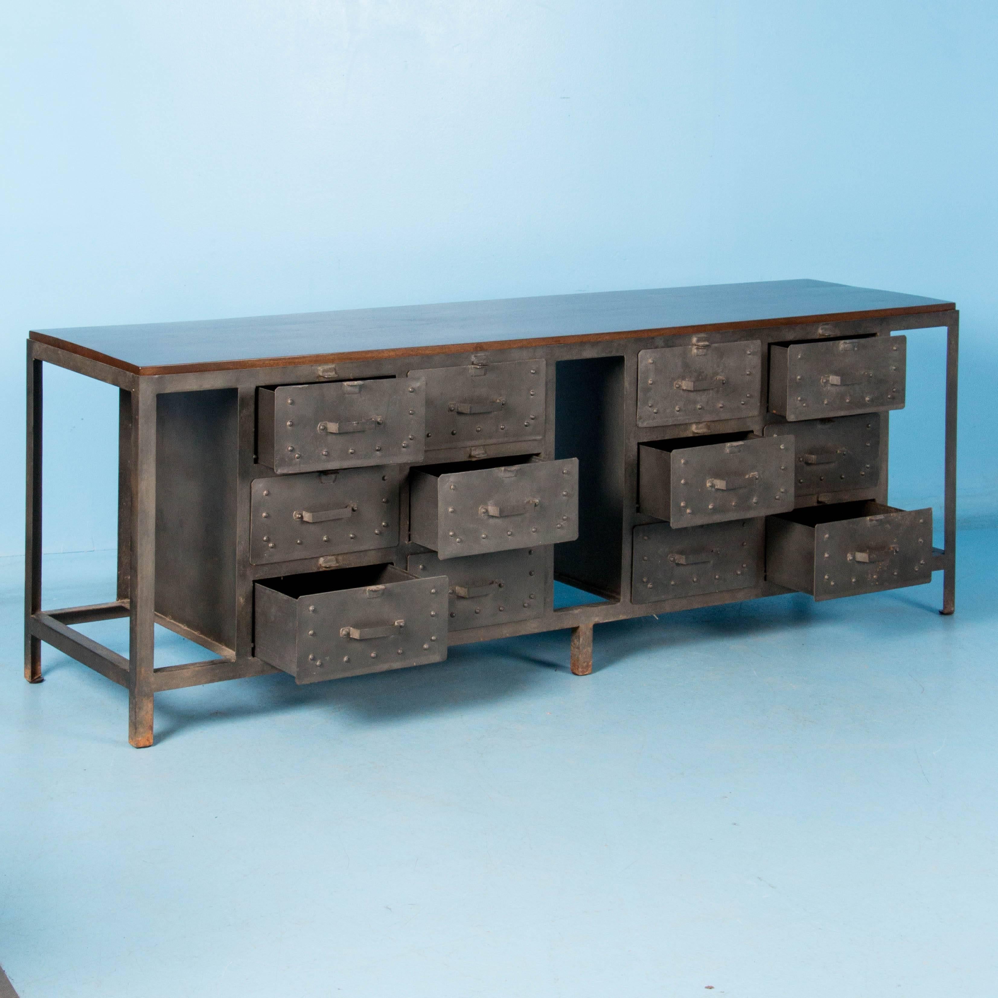 This new Industrial style sideboard features 12 drawers, each with a simple handle and riveted detail. The top, which is removable and recessed into the gray metal, is sheesham wood, made from the red heartwood. Think of this as a kitchen island,