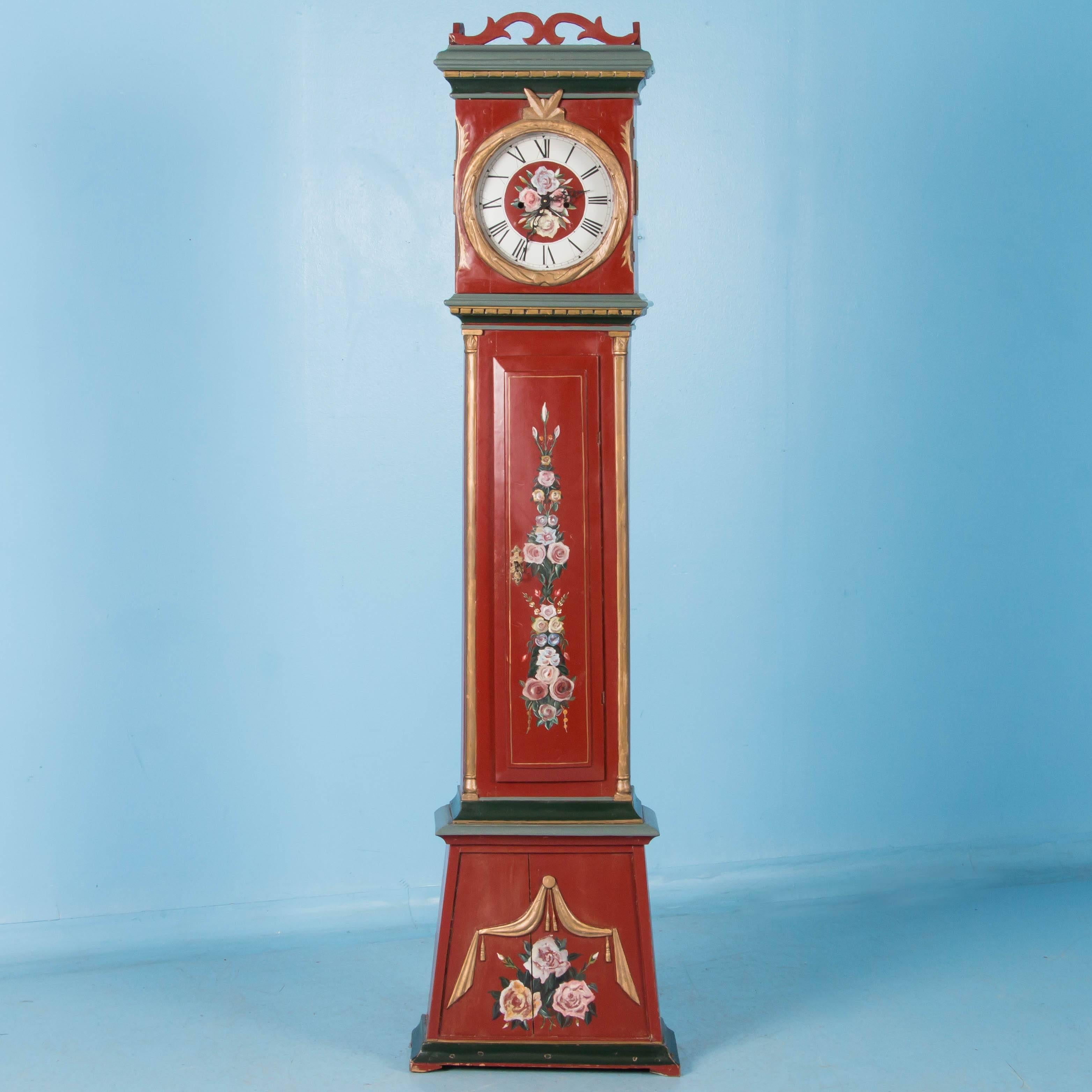 Danish tall clock painted red with accents of green and gold. The red background paint, polychrome accents and floral details are not original but painted more recently. The original clockworks have been removed and a battery pack installed. Please