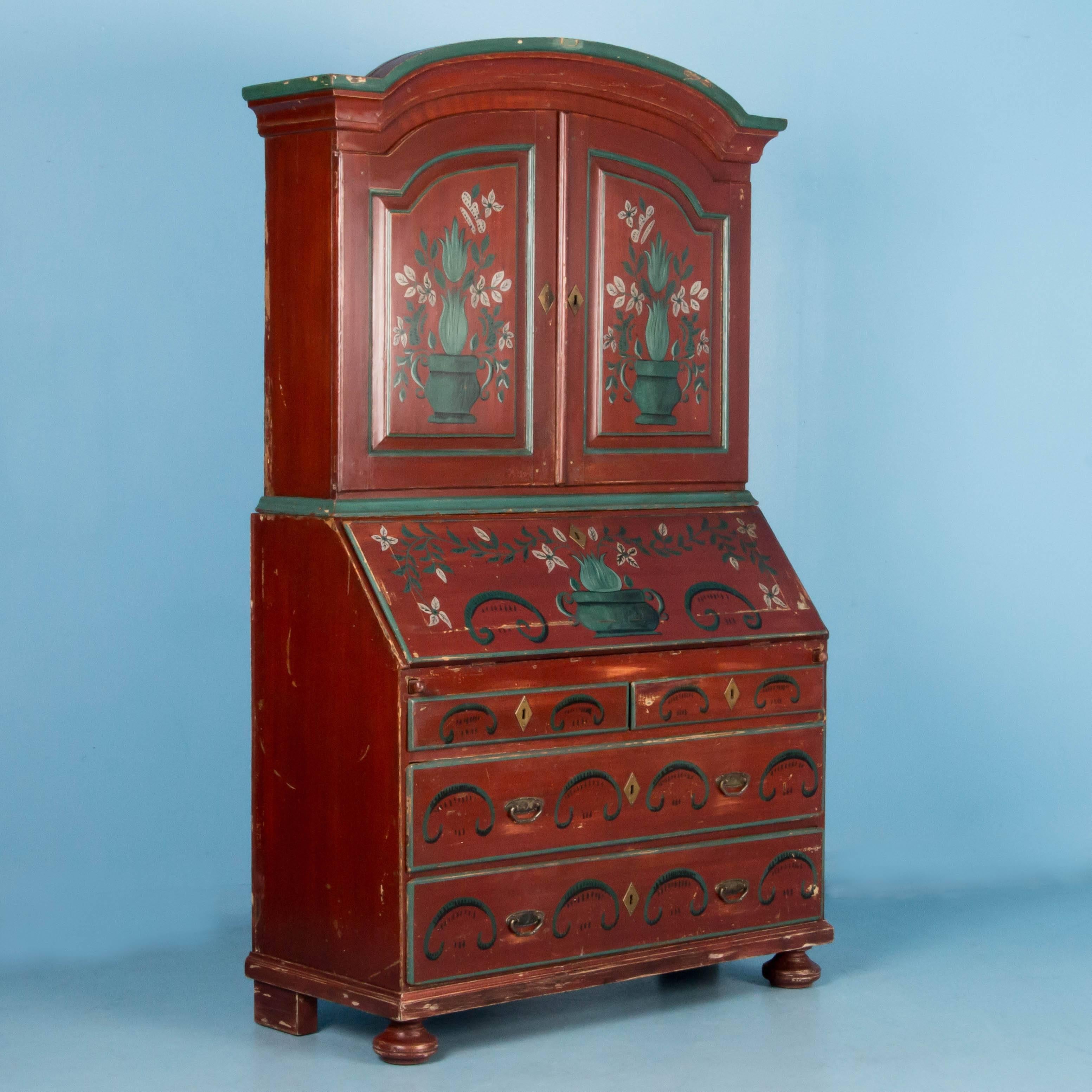 Antique secretary desk from Sweden dated 1897, with original paint and floral decorations made in two sections. Below the arched pediment are two raised panel doors with three fixed shelves inside. In the lower cabinet are two full and two half