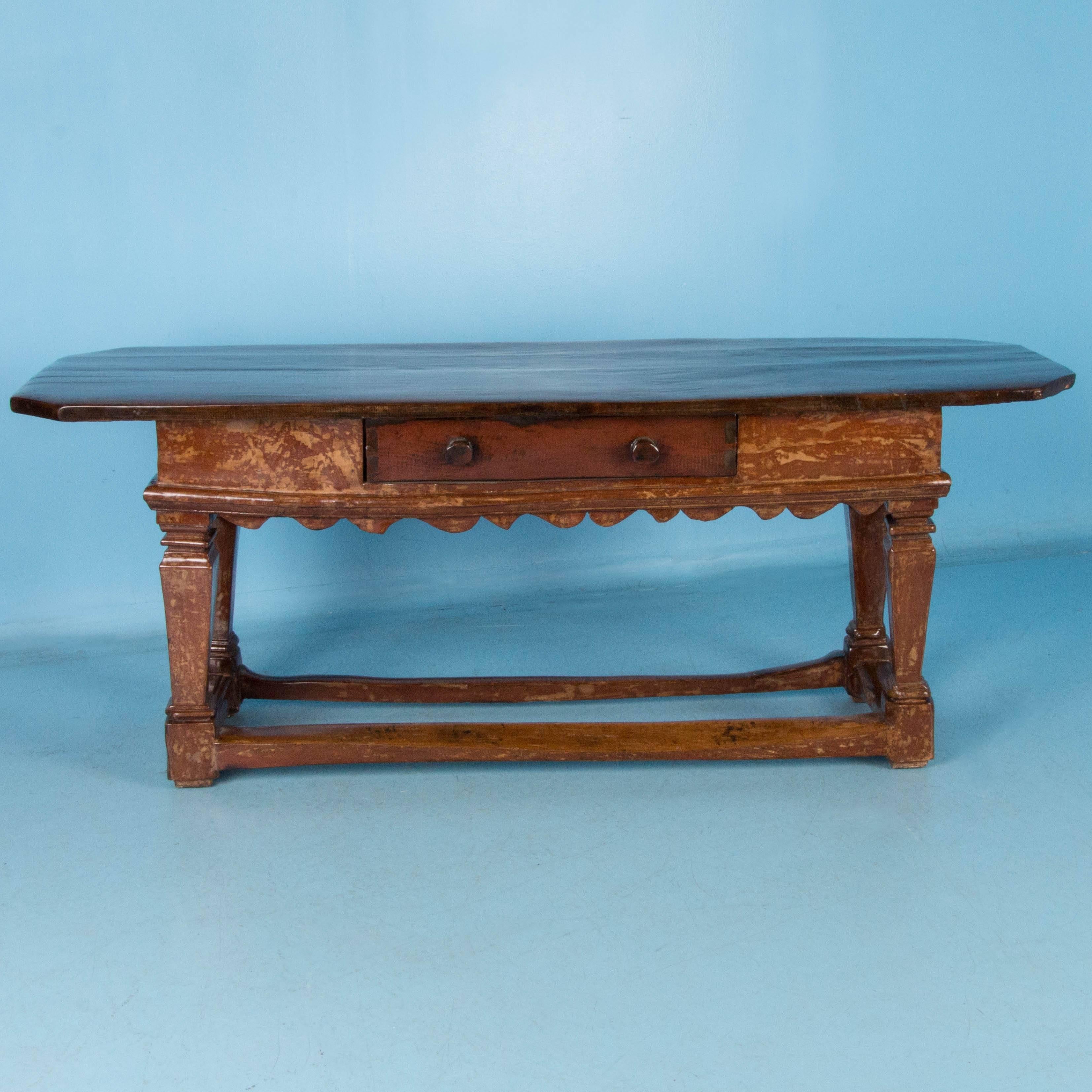 This console or work table from Denmark is solid oak with a gloss lacquered finish enhancing the remnants of old red paint. The four stretchers, connecting the tapered legs with block feet, are original and worn from over two centuries of use. The