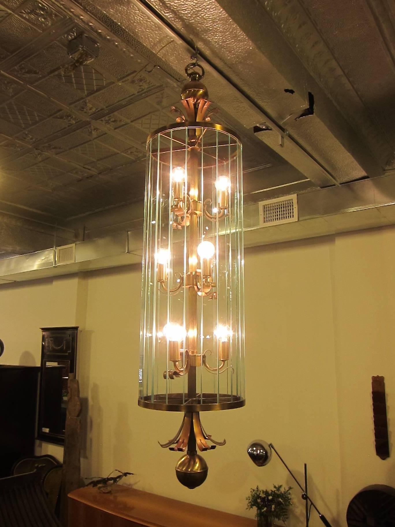A pair of French Art Deco hanging lantern chandeliers. Each lantern has 22 glass insert strips, nine lights, with bronze and brass features. These lanterns are tall at 52 inches and 12 inch diameter, 20th century, France, 1940.  Very beautiful and