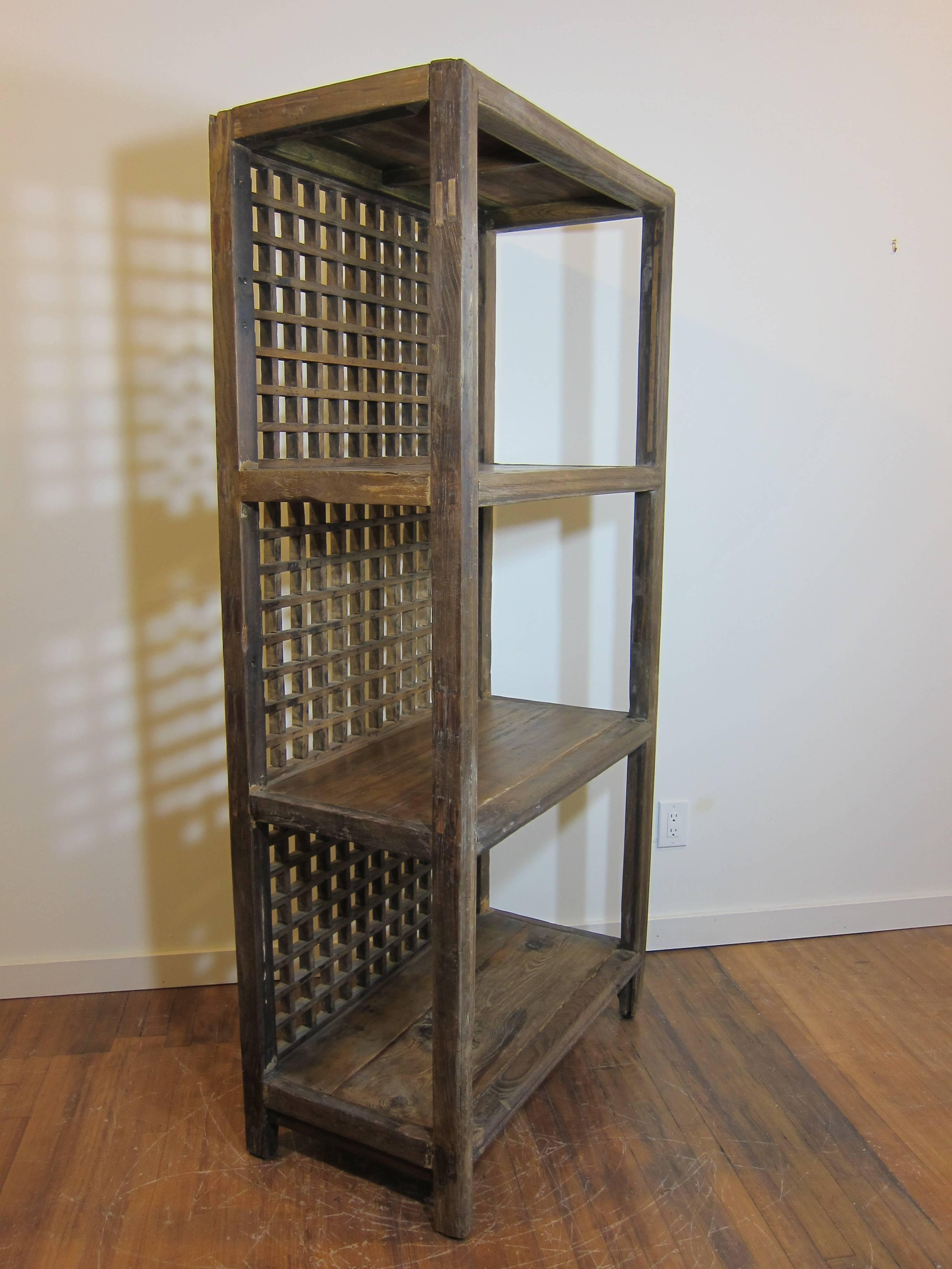 Antique rustic bookcase made of elm wood. Having Lattice style screened back. The elm wood is natural showing ware and age. In good condition. Wonderful rustic piece that will warm any setting.  This is Rustic case piece having exposed wood finish.  