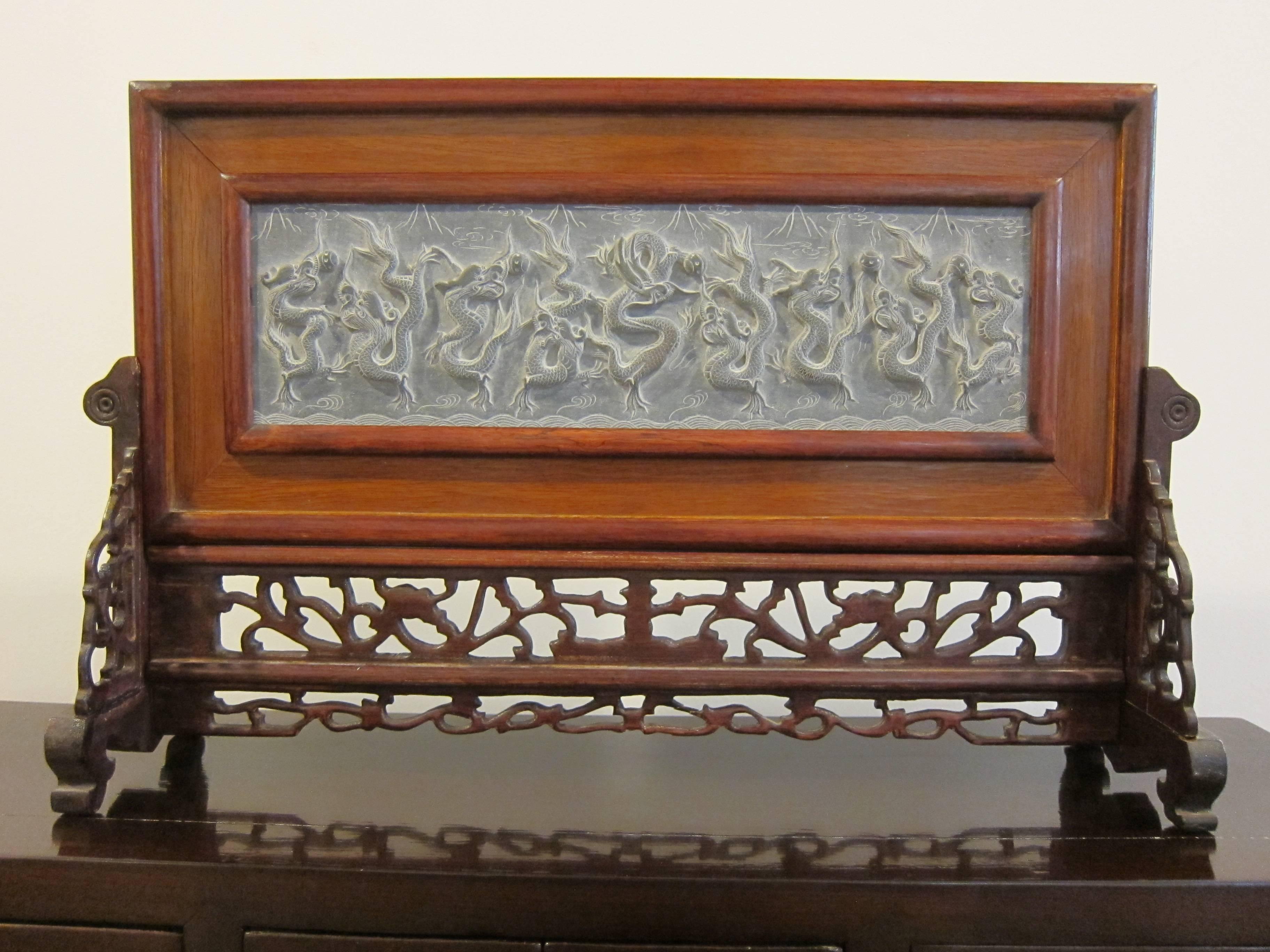 Nine Dragons of Beijing stone carving in rosewood frame with carved rosewood stand. The Nine dragon wall at the Southern end of the forbidden city in Beijing China was built in 1773, the significance of this represents the status of a supreme