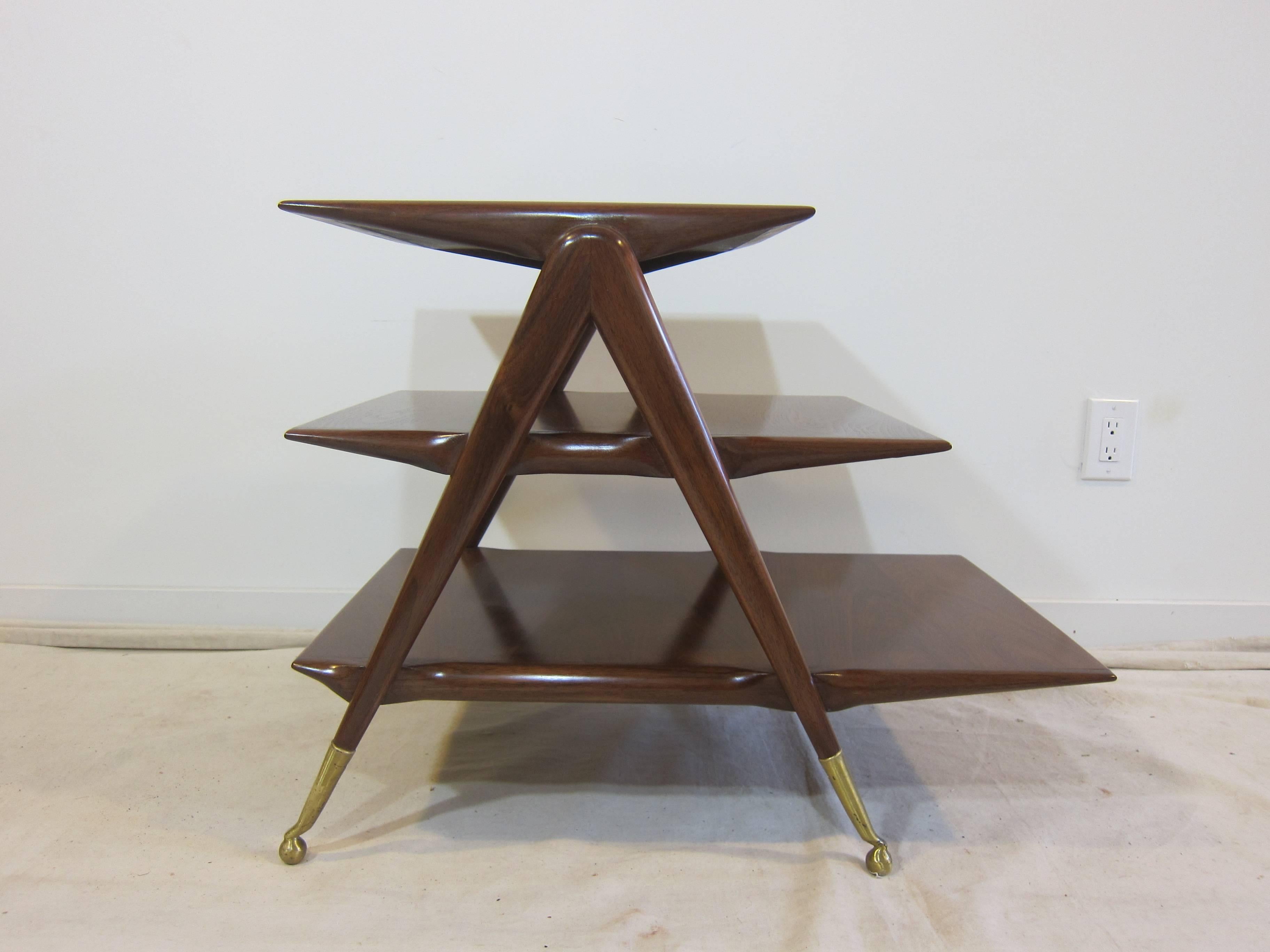 Italian walnut three shelf tiered table in the style of Ico Parisi. Three tiered shelf's of graduated lengths set to a frame structure with brass sabots on brass ball feet, Italy, 1950.  Mid Century in excellent condition.  Magazine table, side