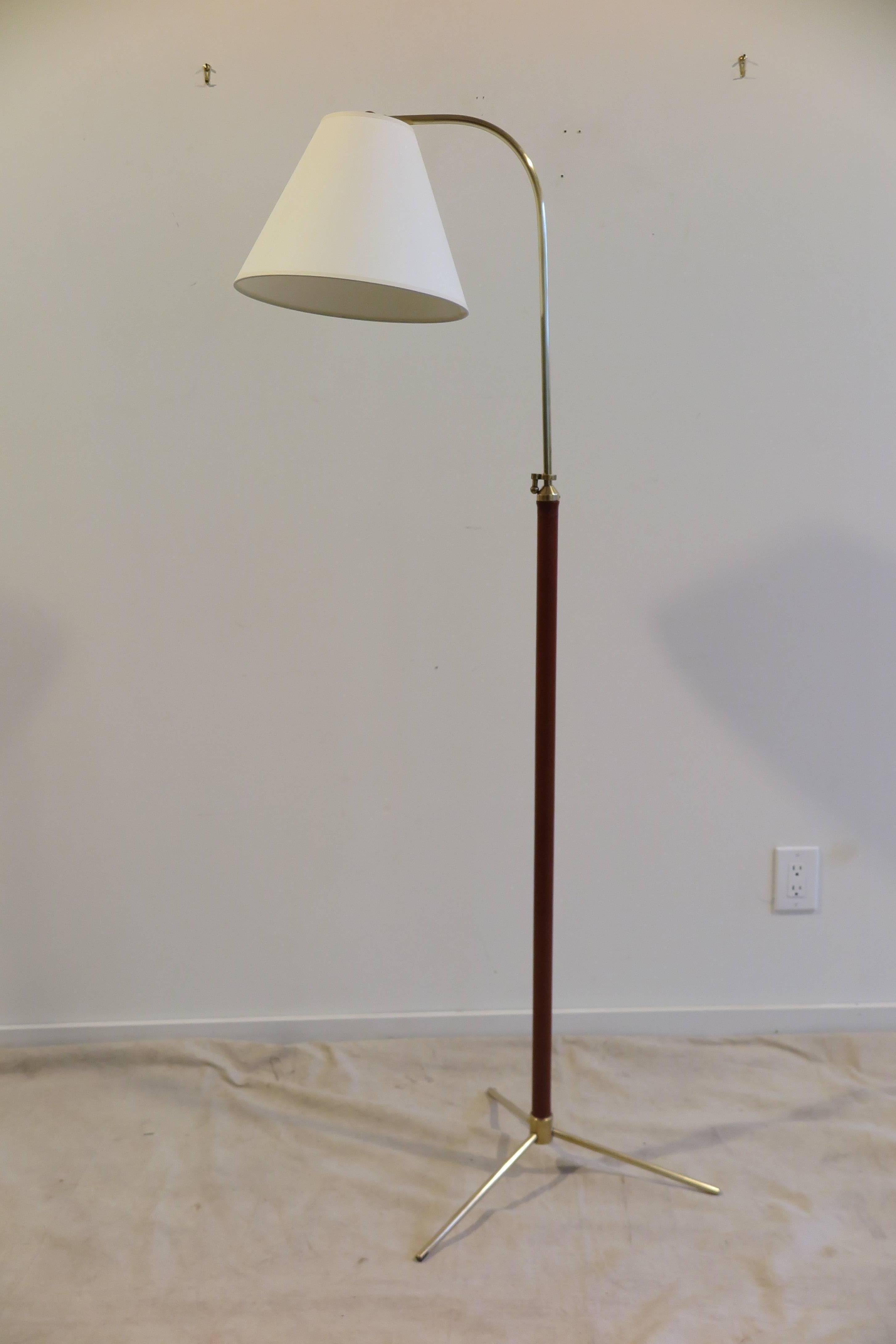 Jacques Adnet leather wrapped brass floor lamp. Adjustable height from 50 to 69 inches. Shade articulates up and down, arm will swivel the shade 360. Solid brass socket with dimmer switch. Brown Leather color. Condition is excellent.