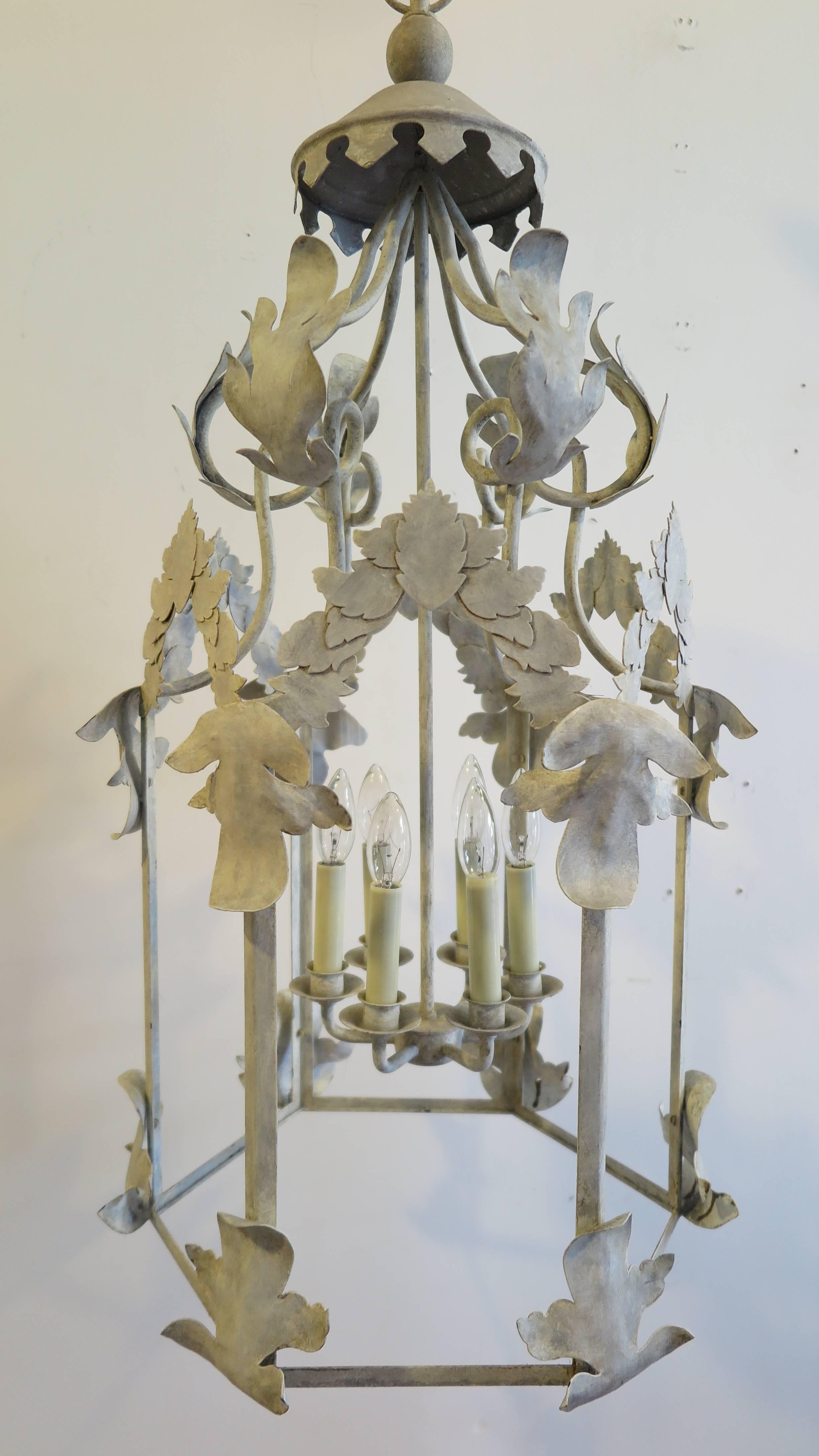 Mid-Century lantern chandelier French style. Iron having an off-white weathered faux patina, decorated with a wonderful motif of leafs, having six candle style lights. A handcrafted piece in very condition. Height is 36 inches to the top of the