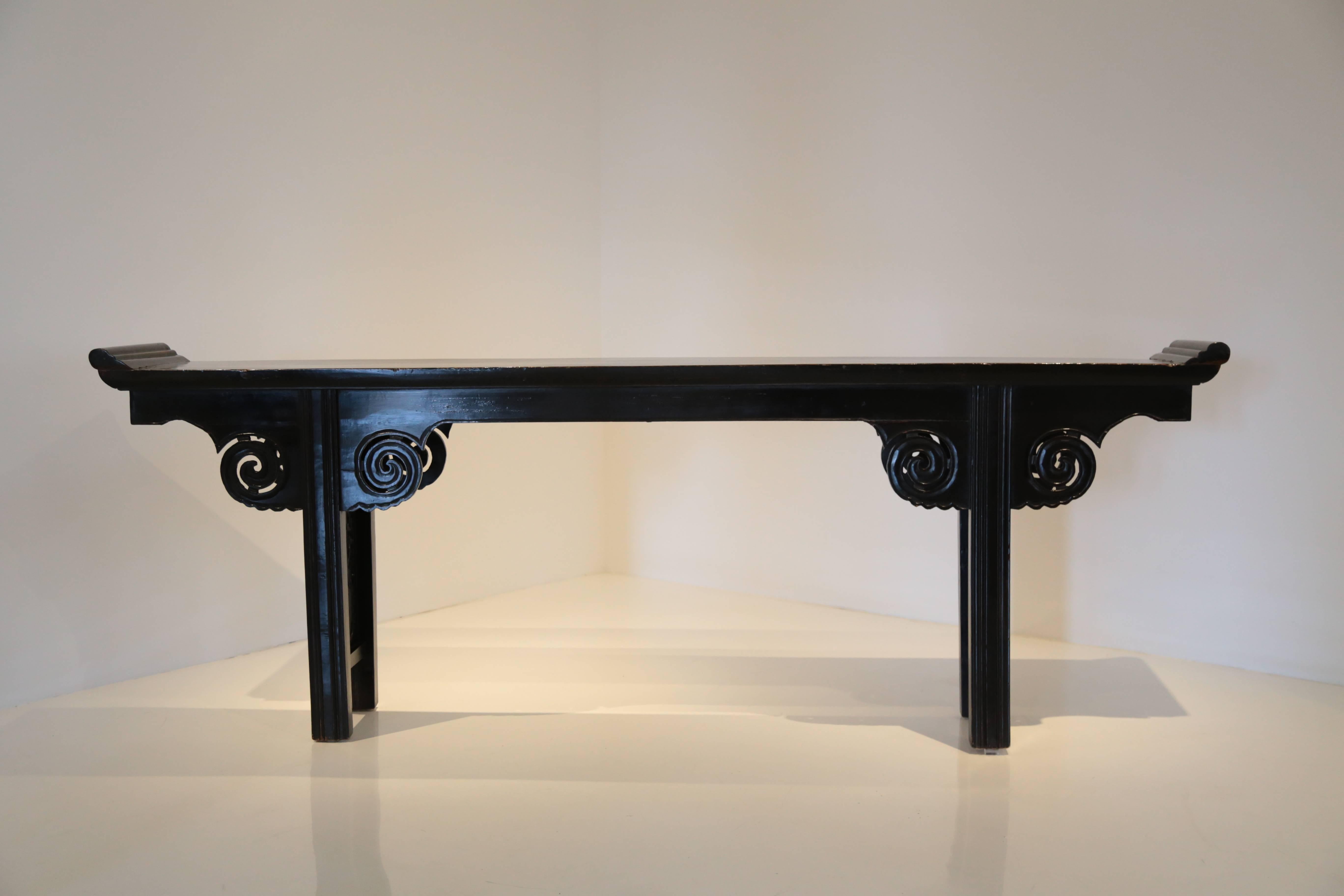  A 19th century Chinese Altar Table, console table.  Exquisite Black Lacquer Chinese Altar Table.  Details carved spandrels of auspicious billowing clouds rest beneath a solid one piece top with everted flanges opening to the heavens.   Carved Penny