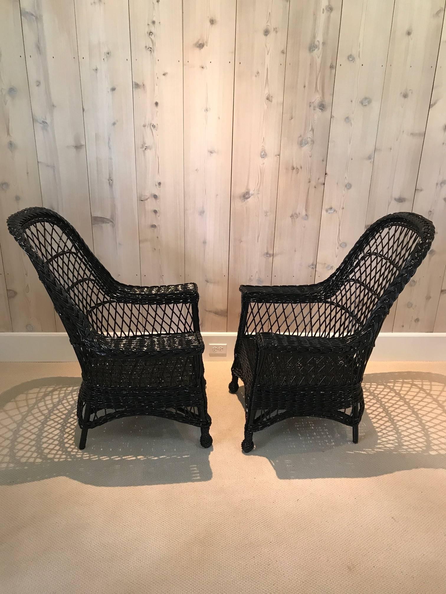 A pair of antique wicker chairs woven of willow by Paine Furniture in fresh black paint.