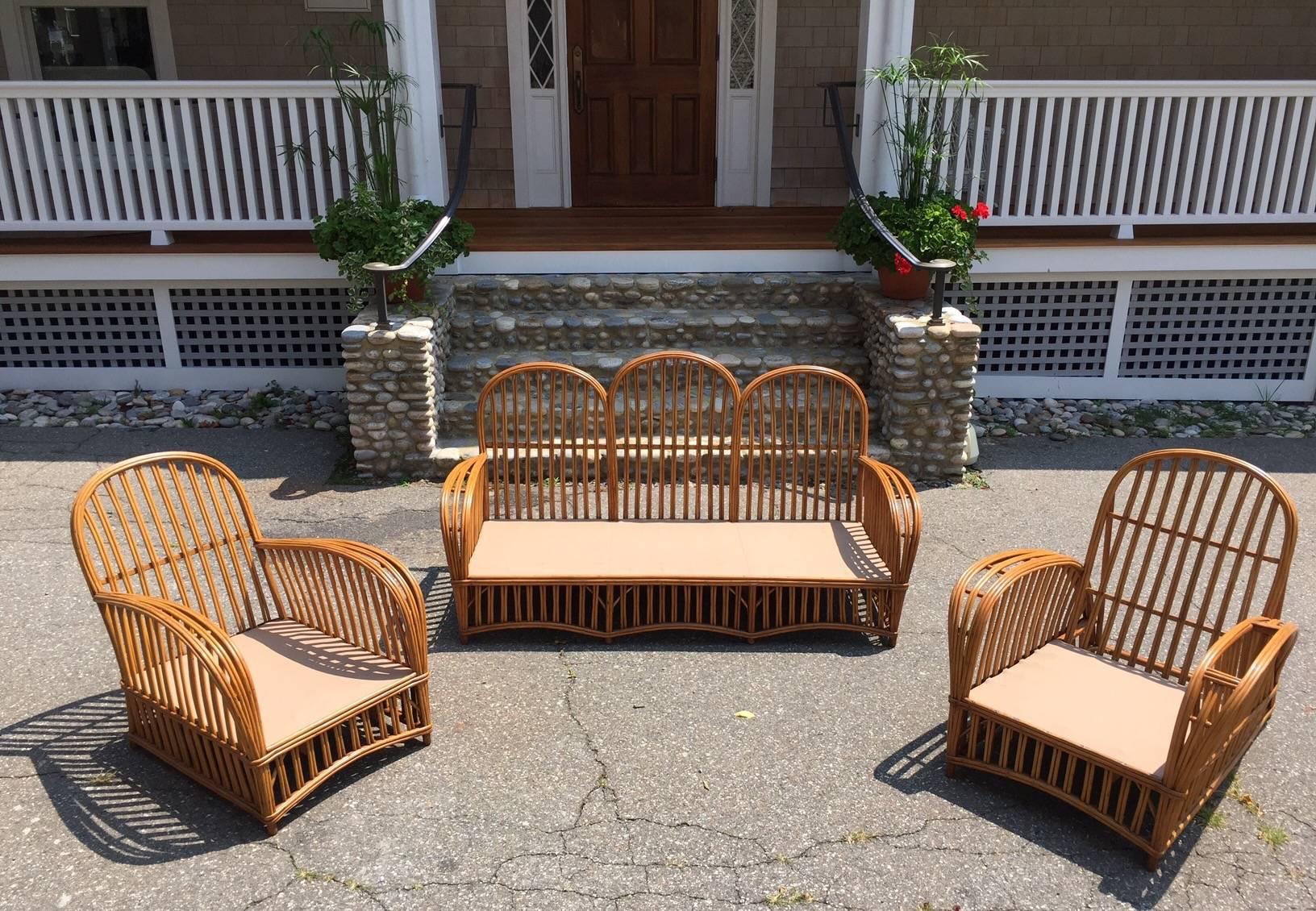Antique stick rattan set in a natural stained finish comprised of one sofa and two lounge chairs. Sofa measures 68