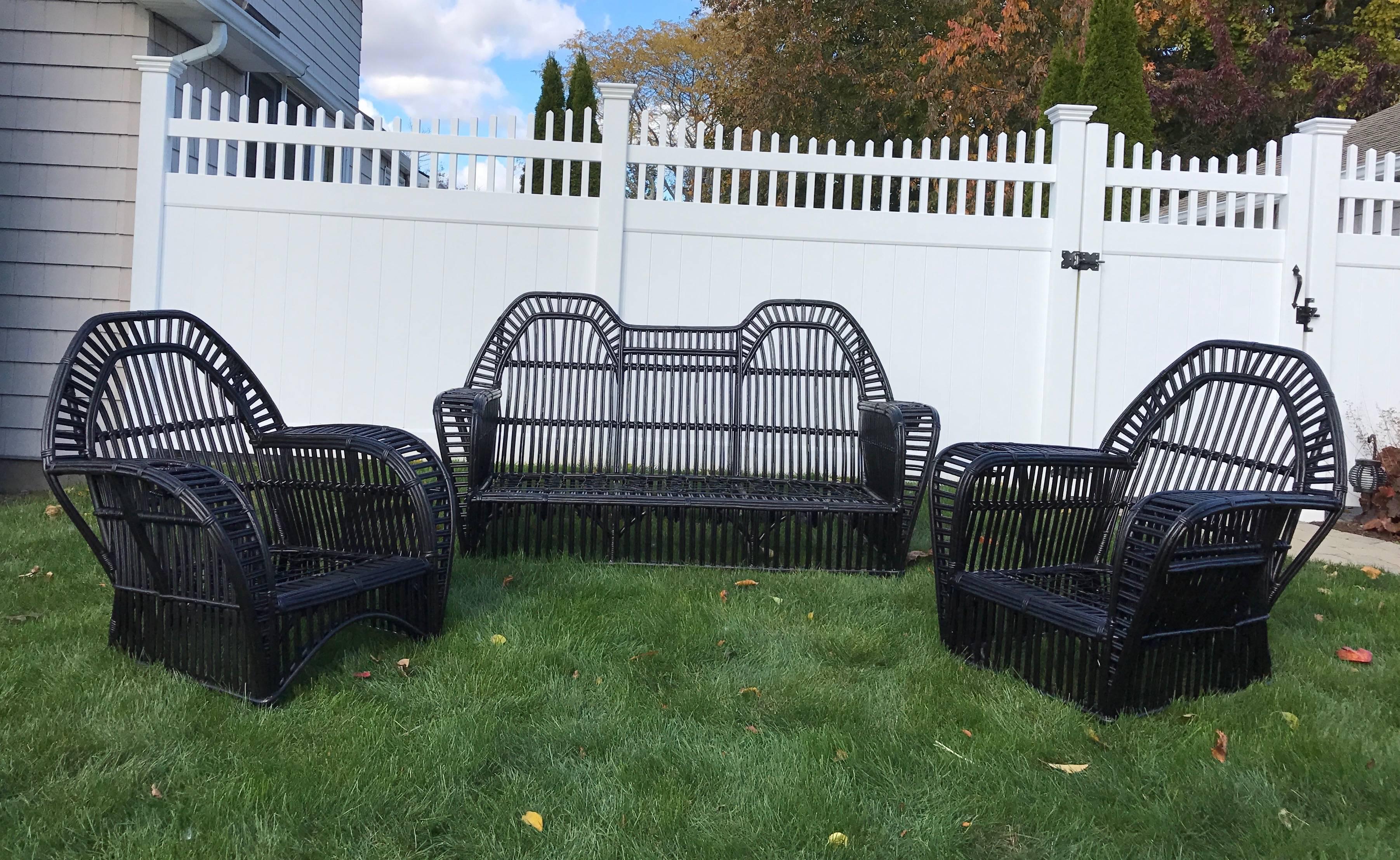 Four-piece antique stick rattan set in black paint. Sturdy and comfortable seating with matching table. Pieces have full skirt on all sides for optimal room placement.
