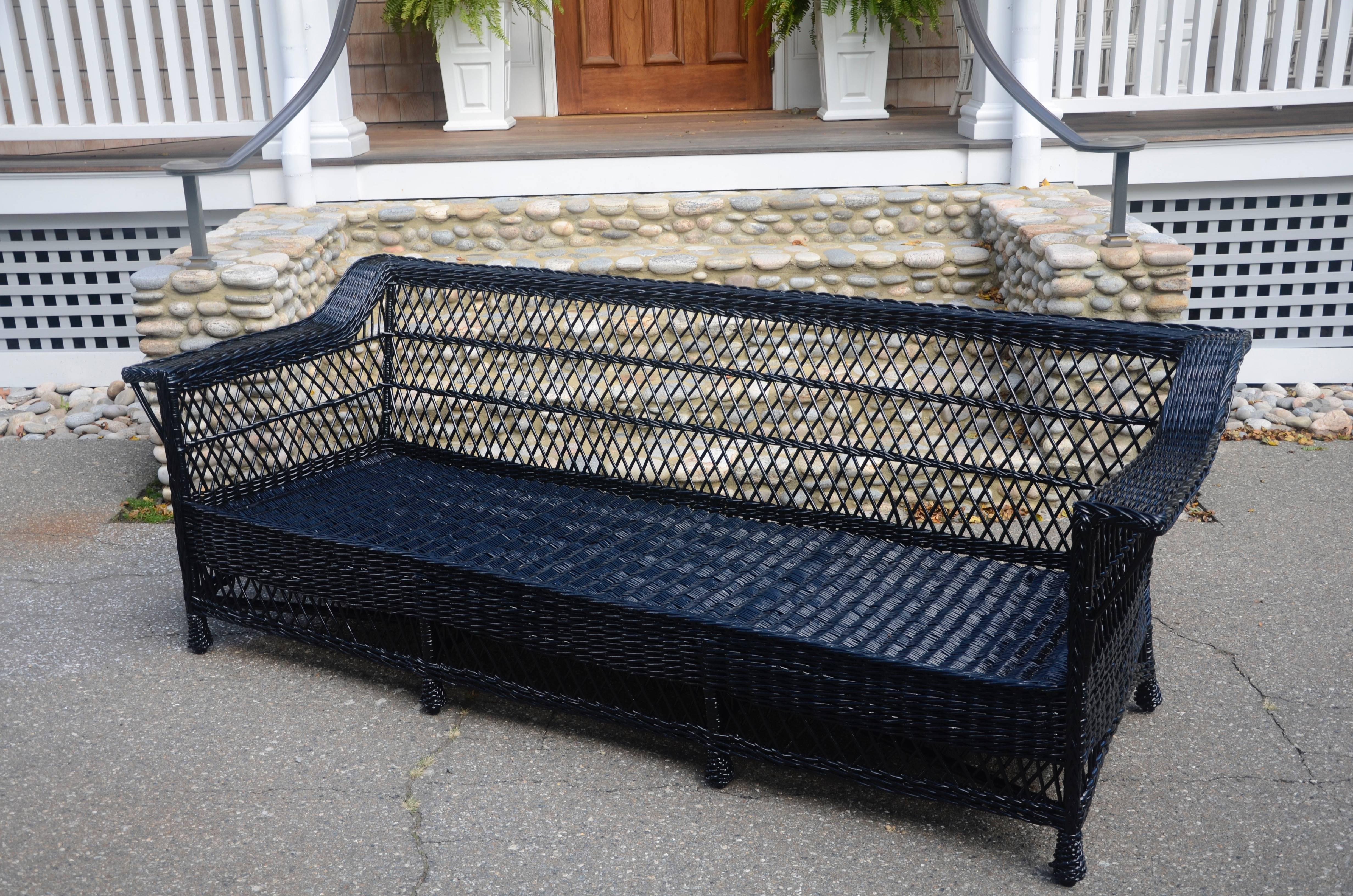 Very large, antique Bar Harbor wicker sofa woven of willow in fresh black paint. Piece measures 92 inches wide, 32 inches tall and 36 inches deep. Seat measures 82 inches wide, 27 inches deep and is 13 inches high. Sofas of this size are rare to