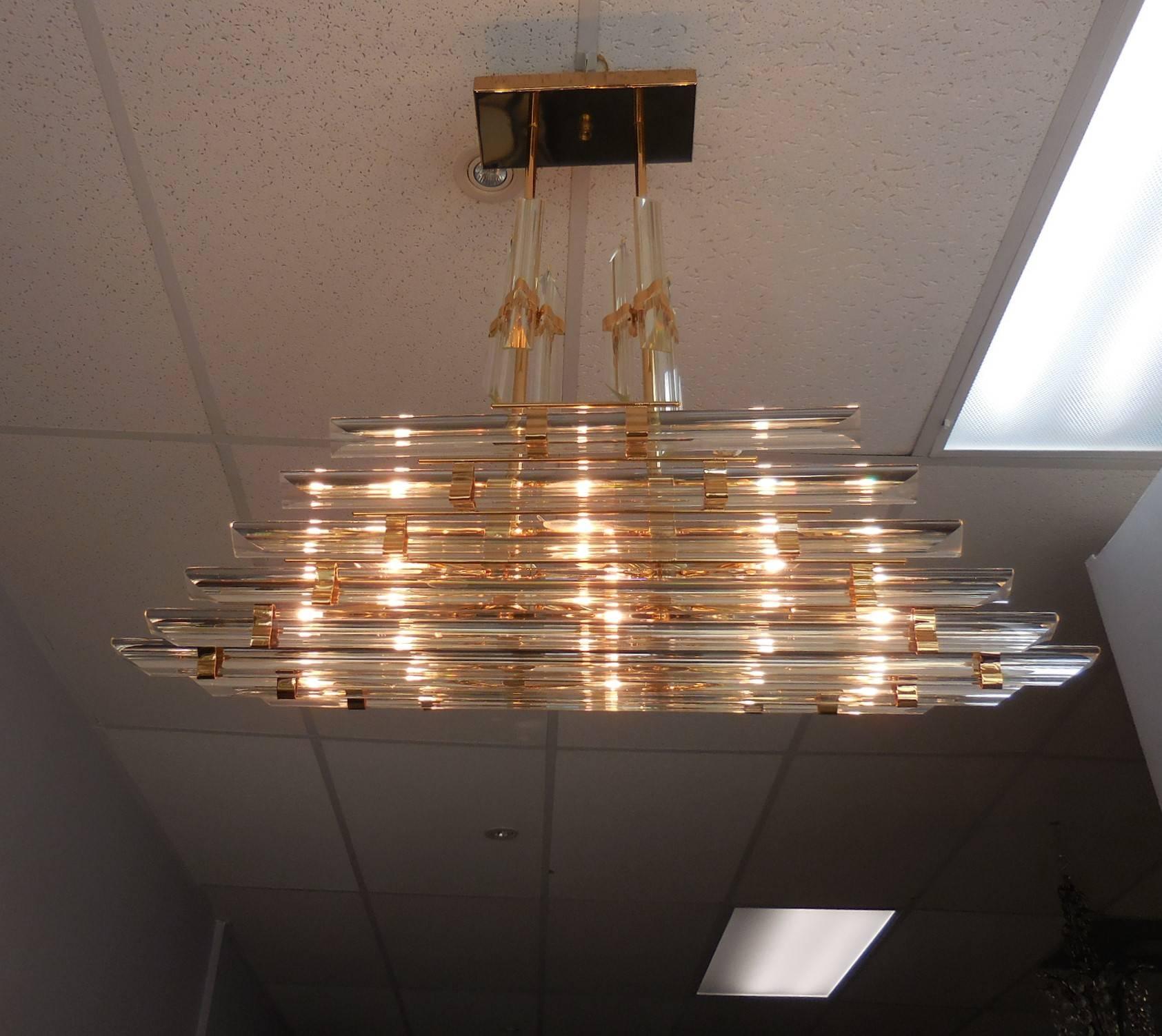 An unusual chandelier. The frame is gold plated, rectangular ceiling plate. The glass rods are of different lengths. Takes eight regular chandelier bulbs. It is a piece of jewelry hanging from the ceiling.
