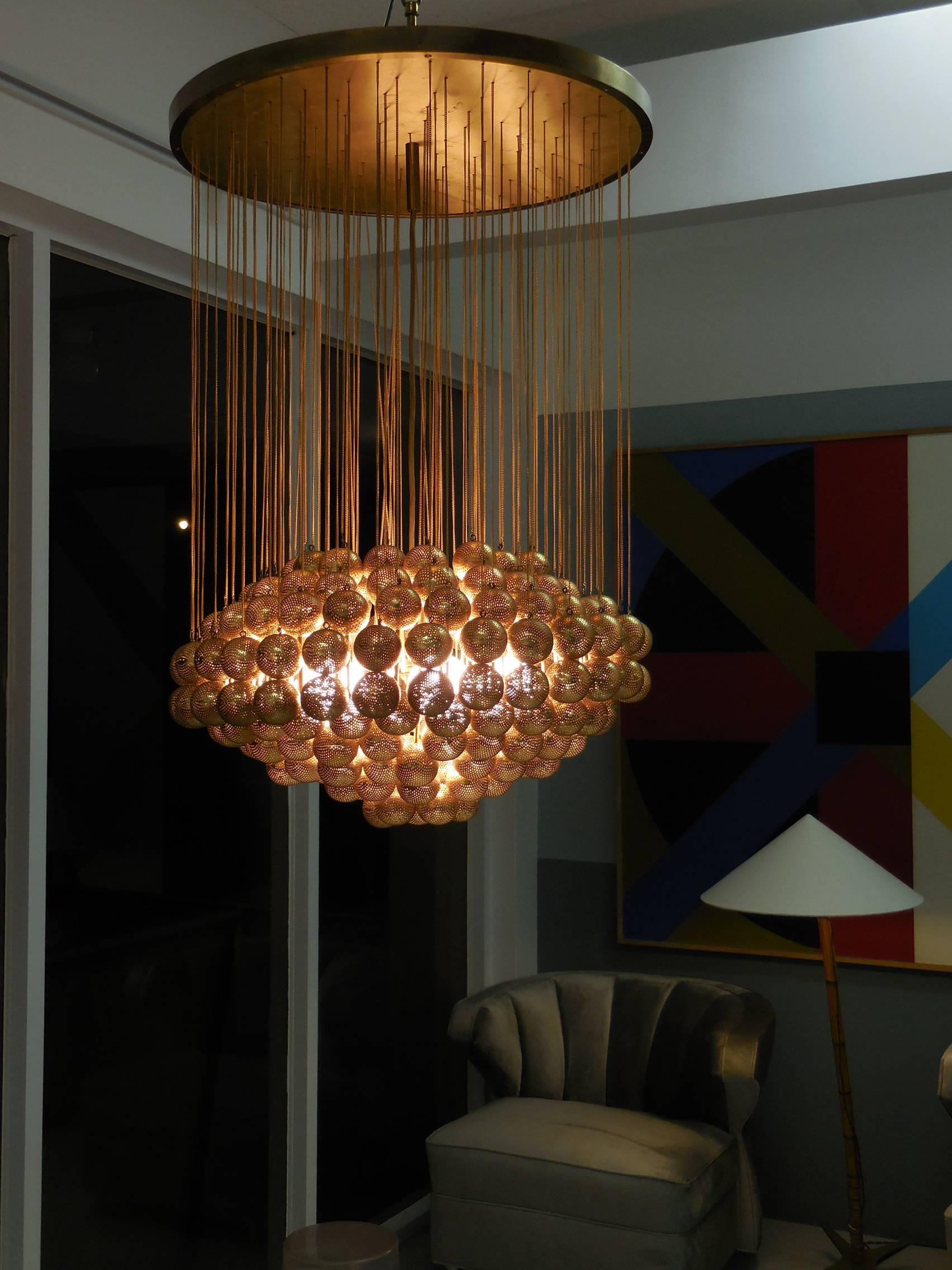 This is an spectacular chandelier. Large brass-plate with lots of hanging perforated brass spheres, the look is very unique and quite stunning. Crafted by Zero Quattro in Milano, Italy, retains creator's tag.