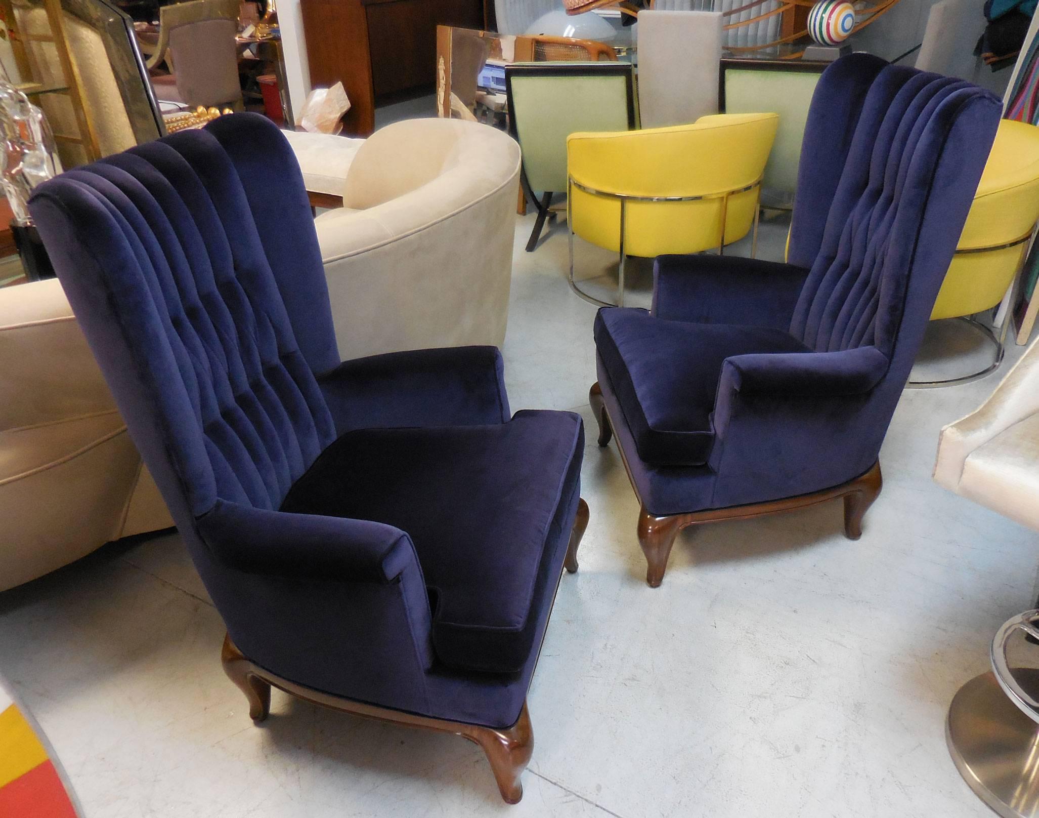 A pair of high back lounge chairs with beautiful tufted backs on solid carved wood bases. Very nice detail, note the robust yet graceful bases and the square shaped arms.