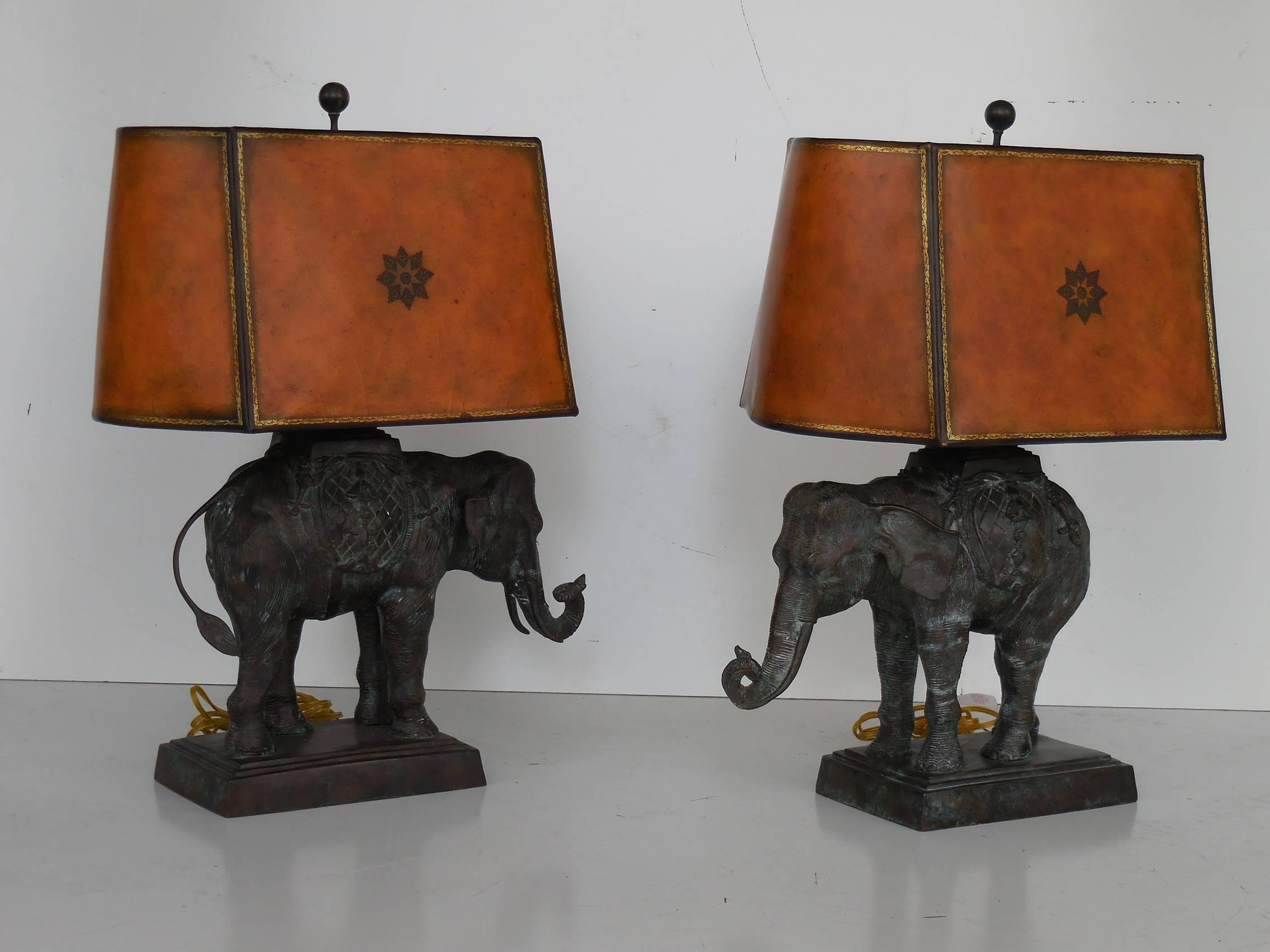 A pair of large bronze lamps by Maitland Smith. Retains original faux leather shades and finials. A true pair, elephants face each other.