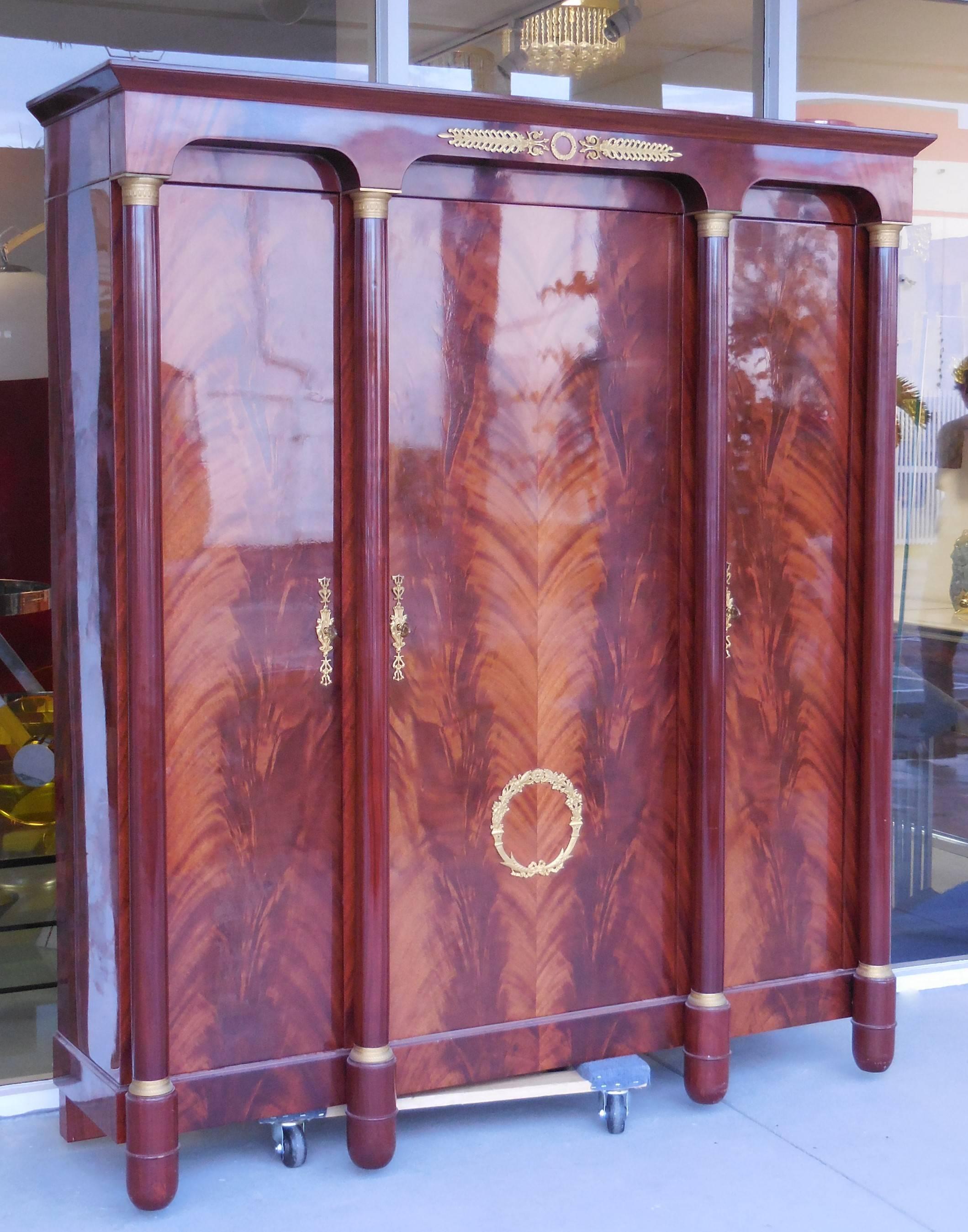 A very stylish and practical armoire. Lots of storage, many adjustable shelves behind the three doors. Finest bronze decoration with very crisp detail. Retains 3 original keys.