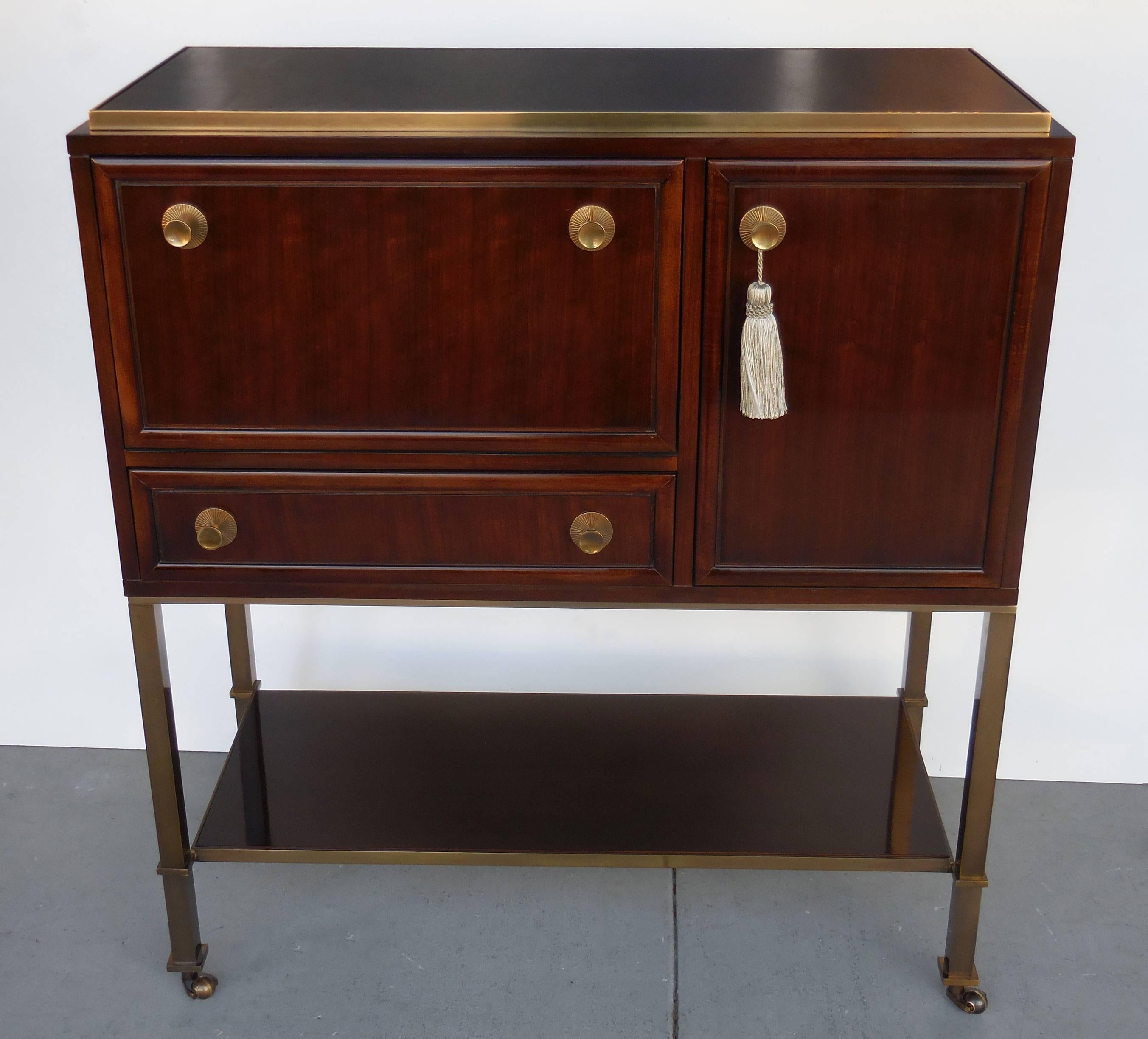 Exquisite cabinet. The base is made of heavy brass with solid brass casters. Pulls are finely cast brass as well as the edge around the leather top. Ample storage, pull down front on bar compartment that also has a mirror on the back, the door
