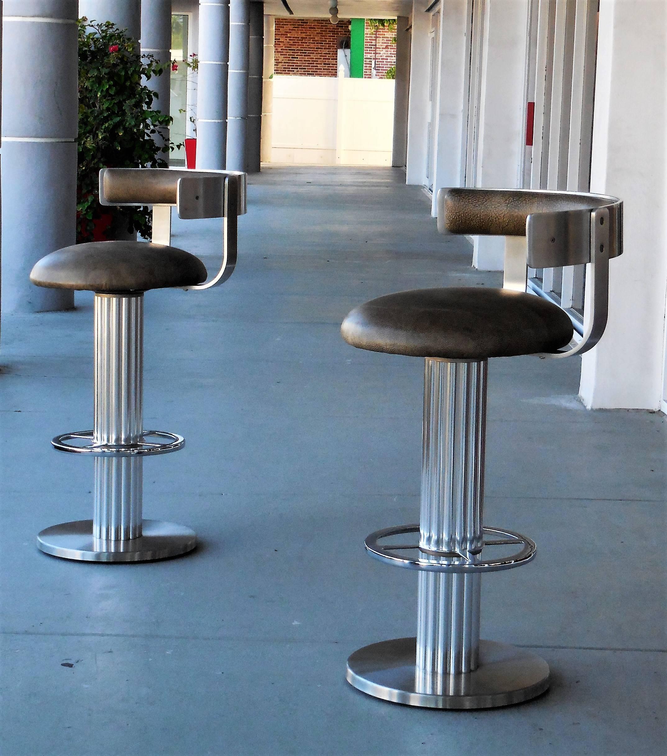 Pair of bar stools by Design for Leisure. The bases are a combination of polished and brushed stainless steel. Wide round leather seats and backs.