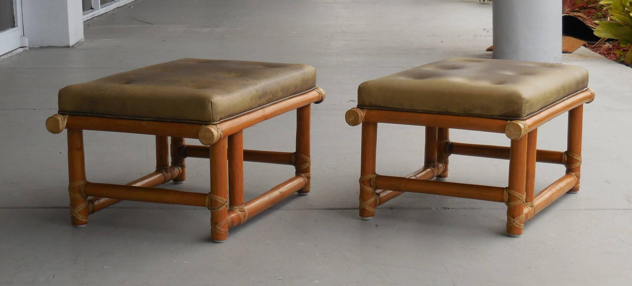 A pair of vintage ottomans or stools by McGuire. Retain the original leather upholstery. Beautiful modernist bases.