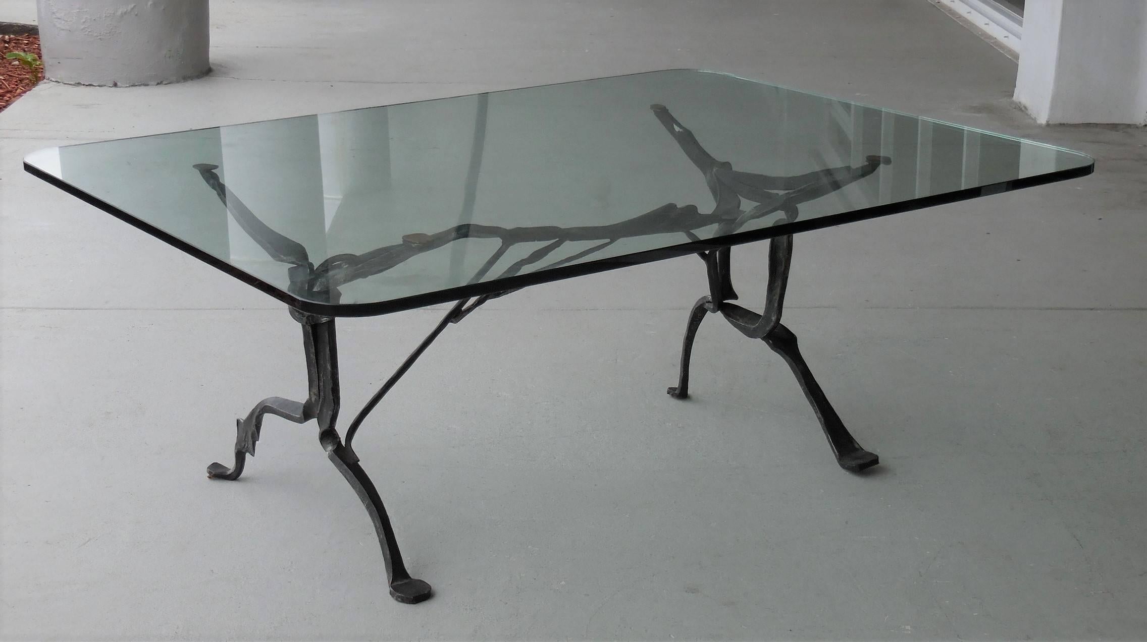 Rare coffee table by Sido and Francois Thevenin for Sawaya et Moroni. Sculptural forged steel base with black patina, original glass top with radial corners. There are small fitted leather pads on feet and arms. Signed with plaque. Sculptural base