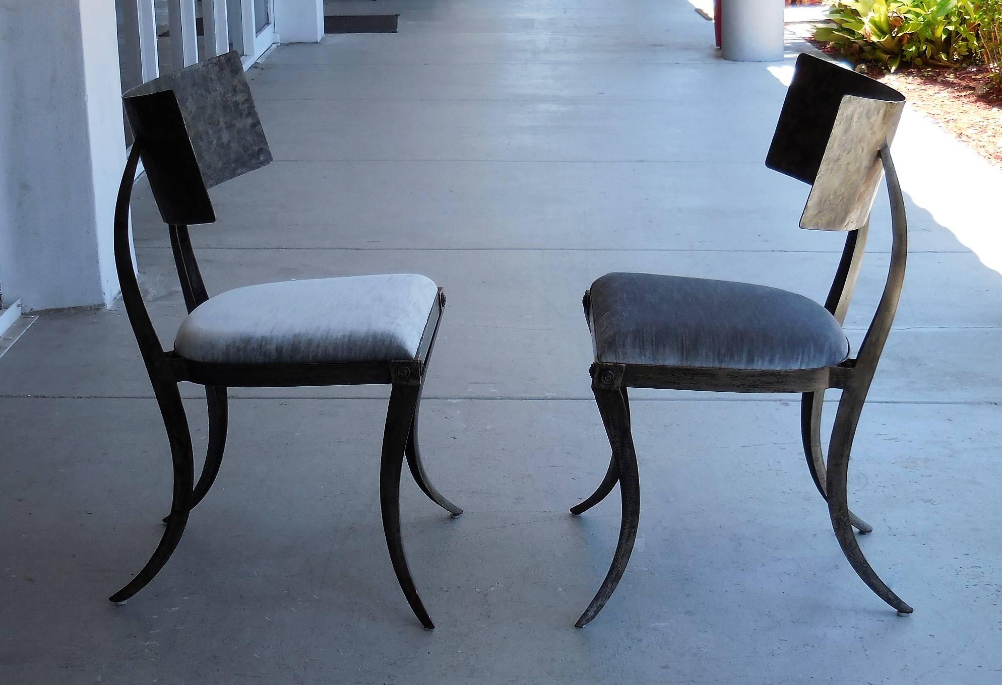 A pair of klismos chairs in patinated steel and upholstered seats. These chairs have a bold and graceful design.