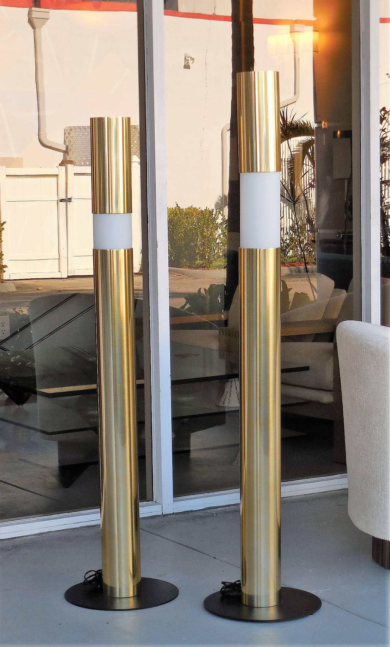 Pair of modernist floor lamps. Cylindrical shape with glass diffusers. The top metal piece moves up and down. Light also comes out at the top. Glass retain 