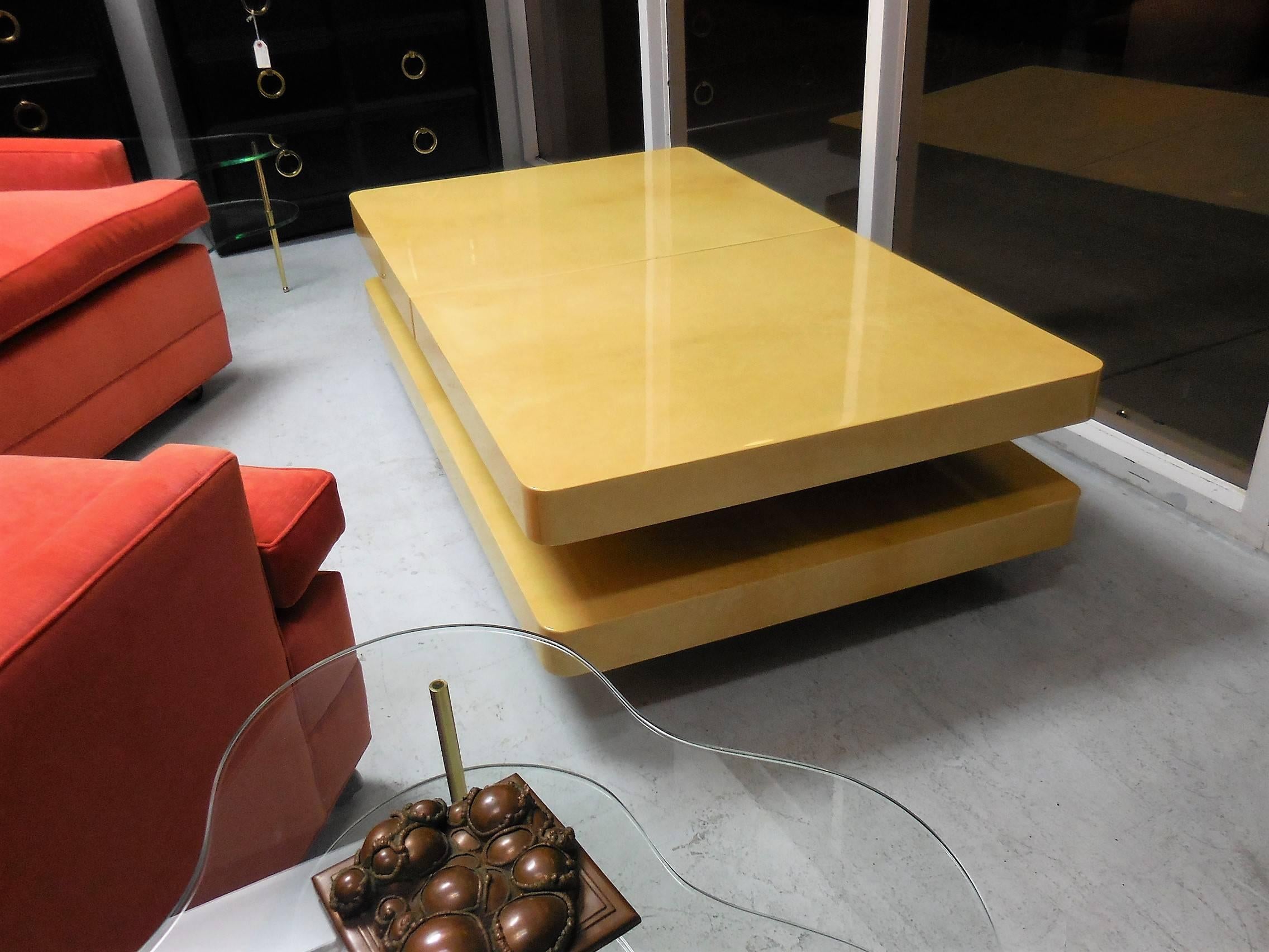 This is an awesome coffee table, the top slide to the sides and reveal a mirrored compartment that could be used as a bar. Quite a novel idea! It is wood meticulously clad in parchment with a gloss lacquer finish. Brass apron.