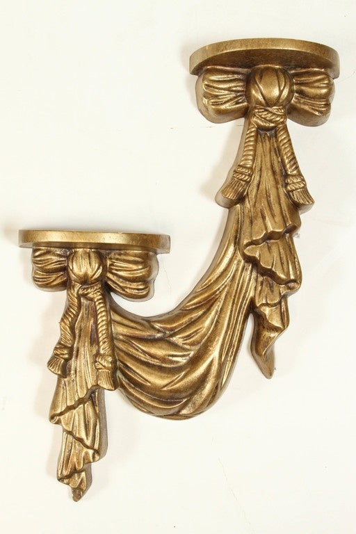 Pair of vintage gilt gold, deco style drape shelves, each with two bows featuring shelve platforms that measure 8