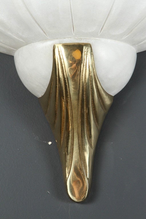 Wall Sconce in the style of Art Deco, with frosted glass shade attached to a polished brass base.