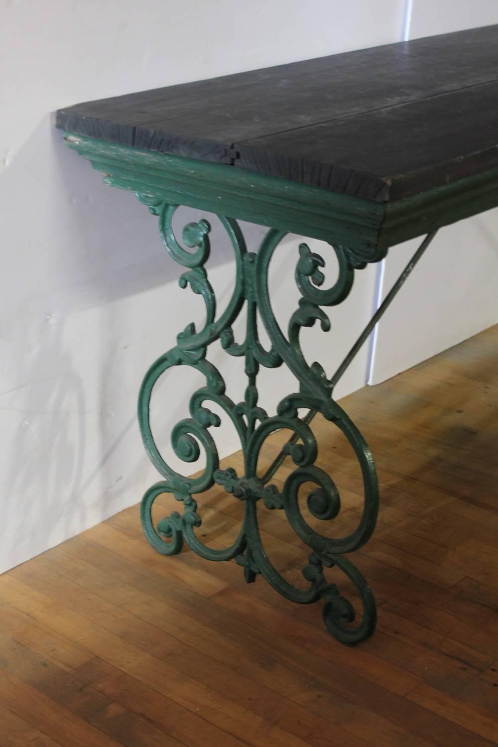 Long antique American department store display table with cast iron base and wood top, 11 feet.