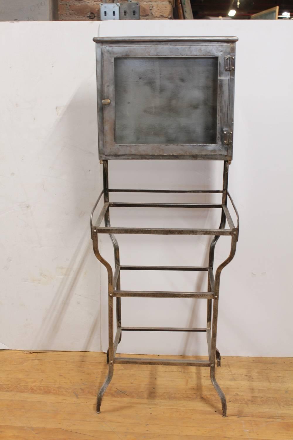 Antique American medical metal cabinet with glass shelves.