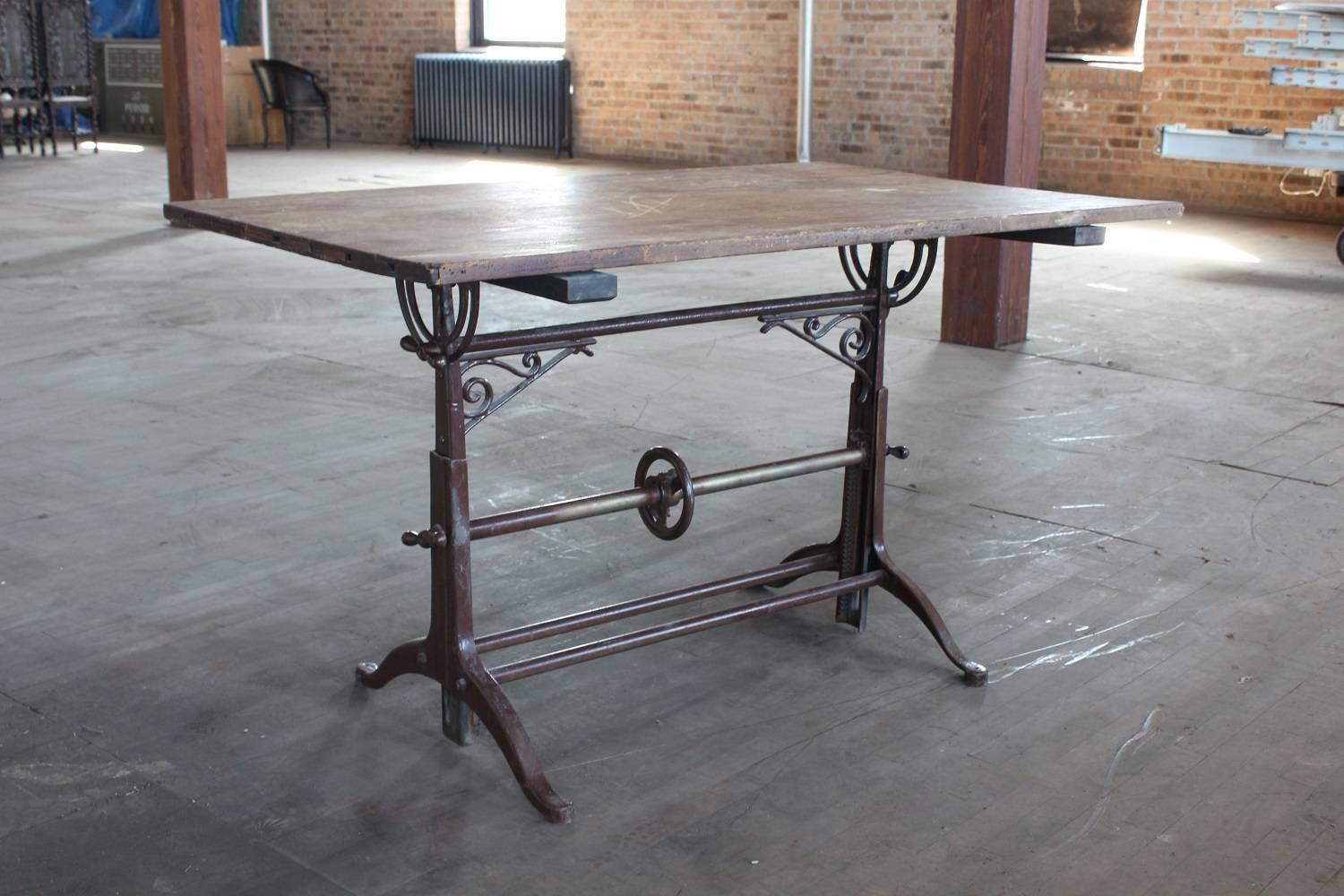 Antique drafting table with cast iron base and wood top. Measures: Height is adjustable from 33.25