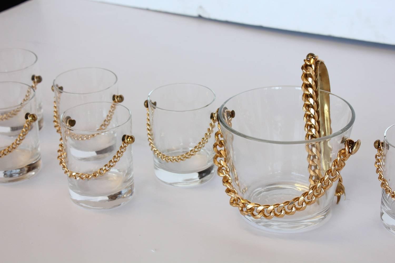 Stylish modern glassware set with brass chain. Set includes ten glasses and ice bucket. Measures: Ice bucket: H: 5