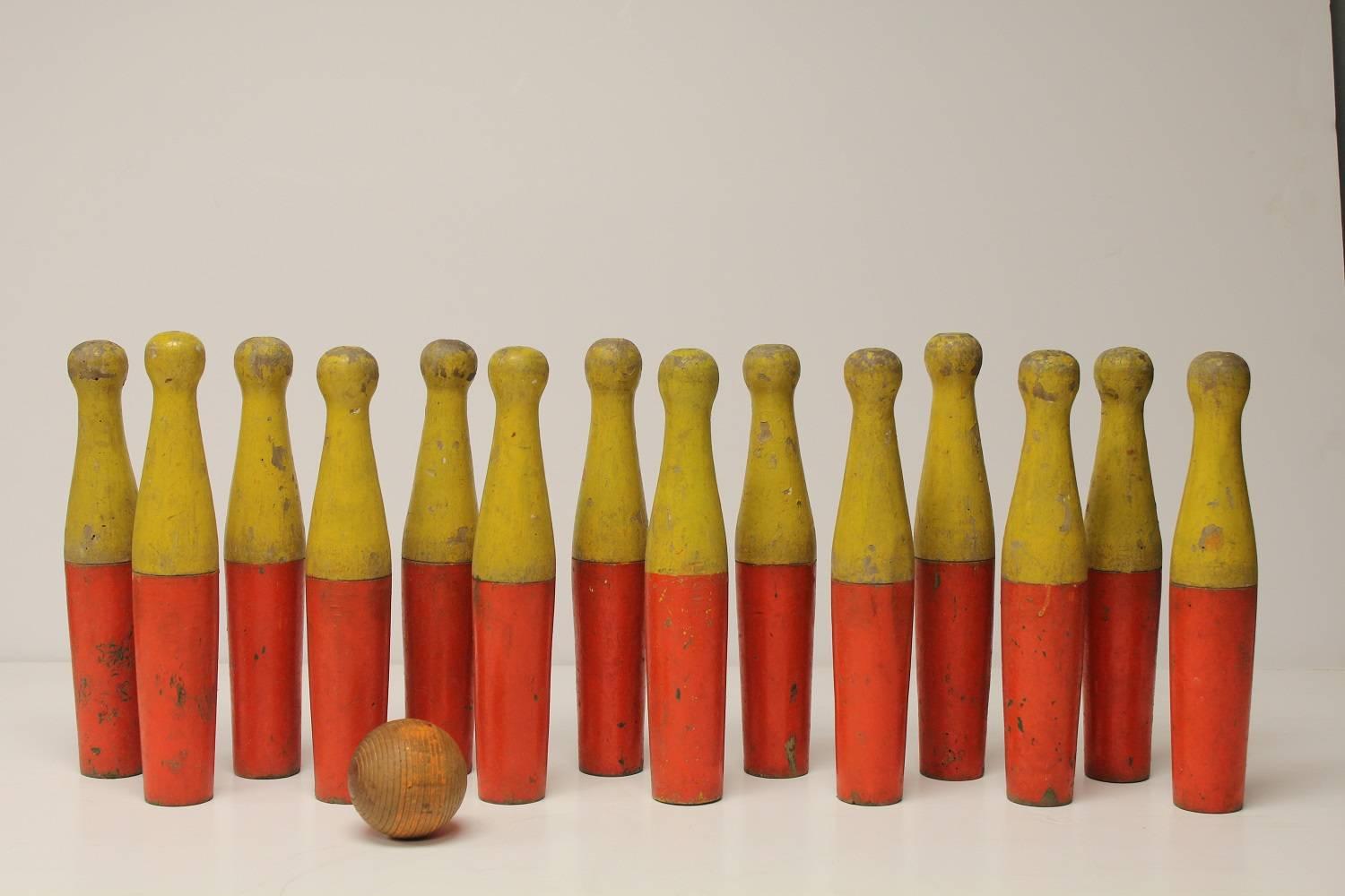 Collection of 14 vintage lawn bowling pins and one ball with original holder. Original paint.