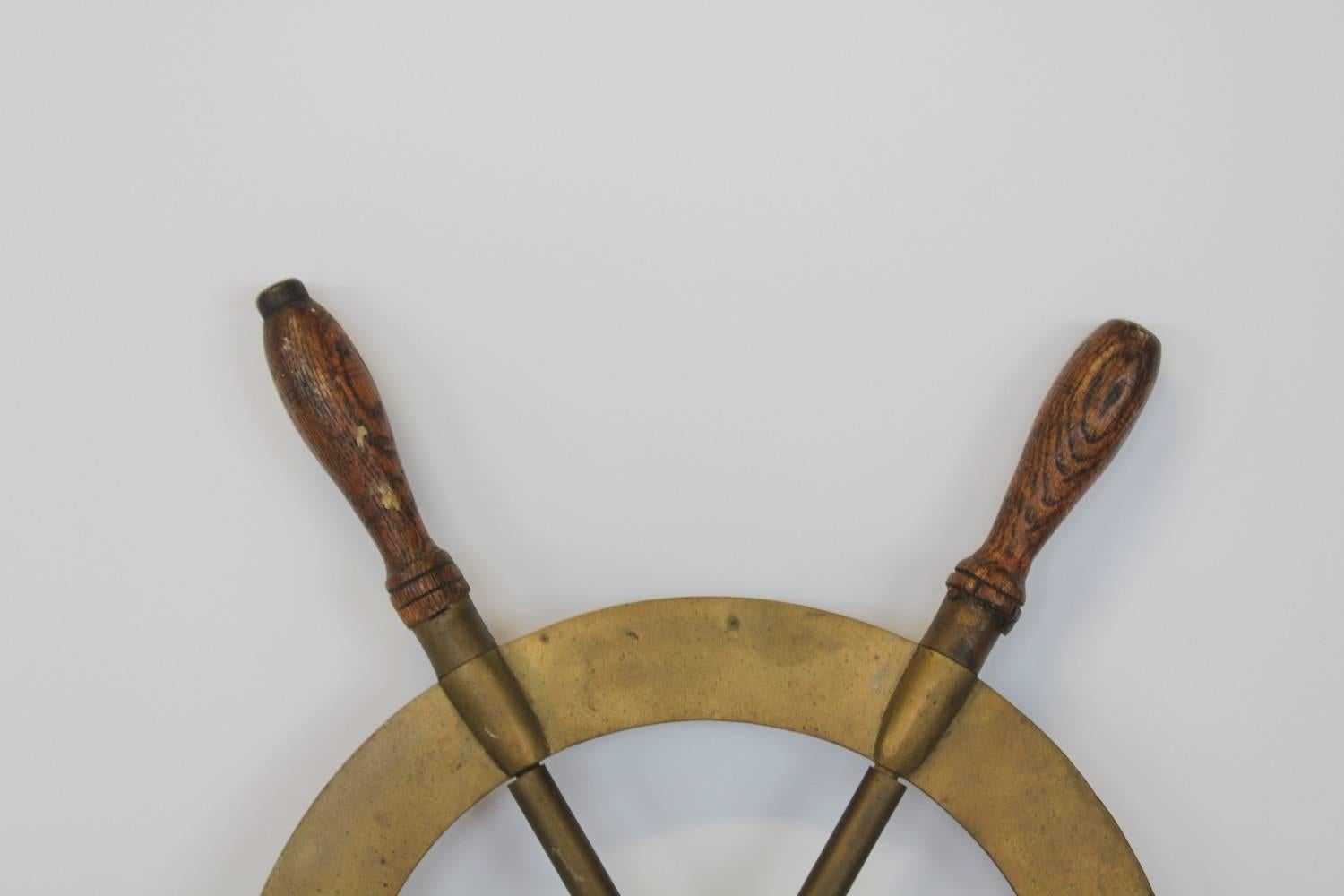 Antique brass boat ship steering wheel with wooden handles.