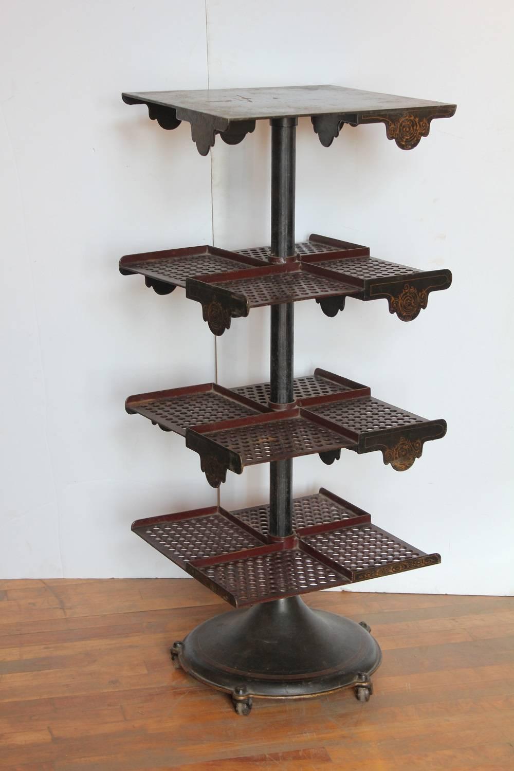 Rare antique cast iron revolving bookstand with original stencils. It has three cast iron perforated and divided shelves. Height is adjustable.