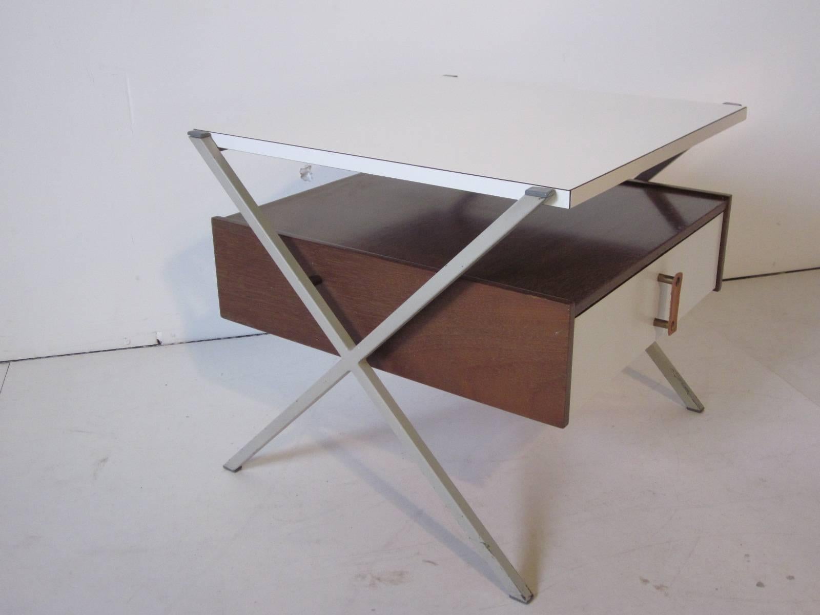 A nightstand or side table designed by Ladislav Sutnar for Knoll - Drake with metal X legs, walnut body, white laminate top and drawer front with brass and leather pull. A rare and hard to find form manufactured by Knoll.