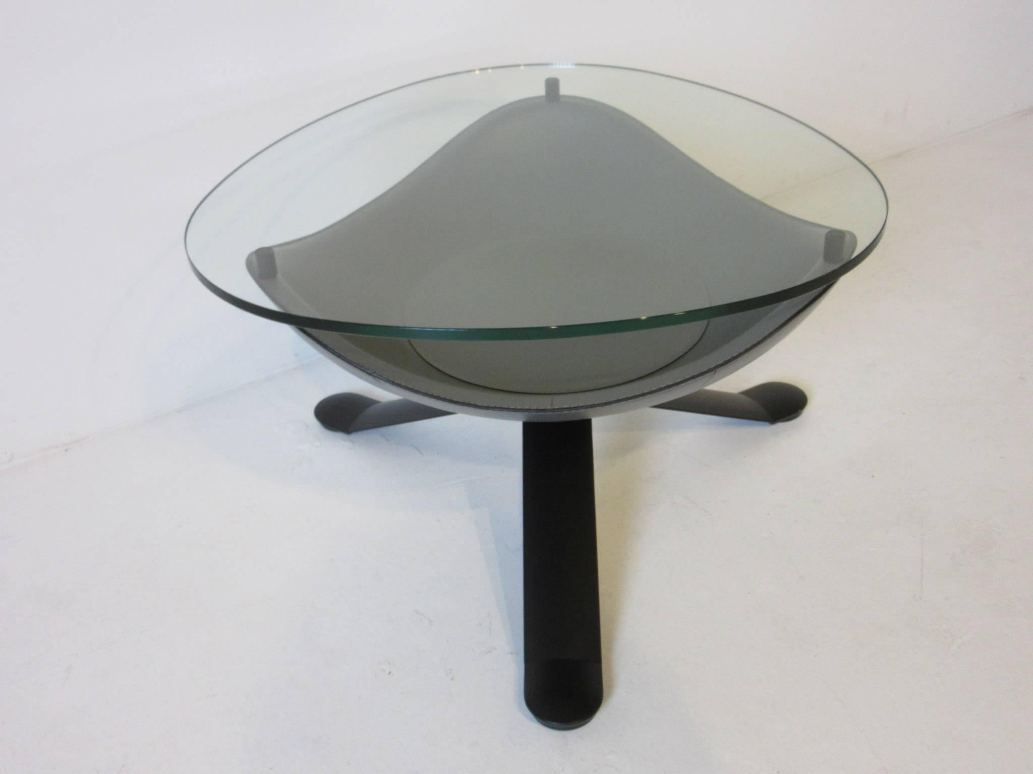A sculptural gray molded and stitched leather with plate glass topped side or coffee table sitting on a three pronged satin black metal base. Designed in a bowl form for a bit of storage under the glass top from Italian designer Matteo Grassi.