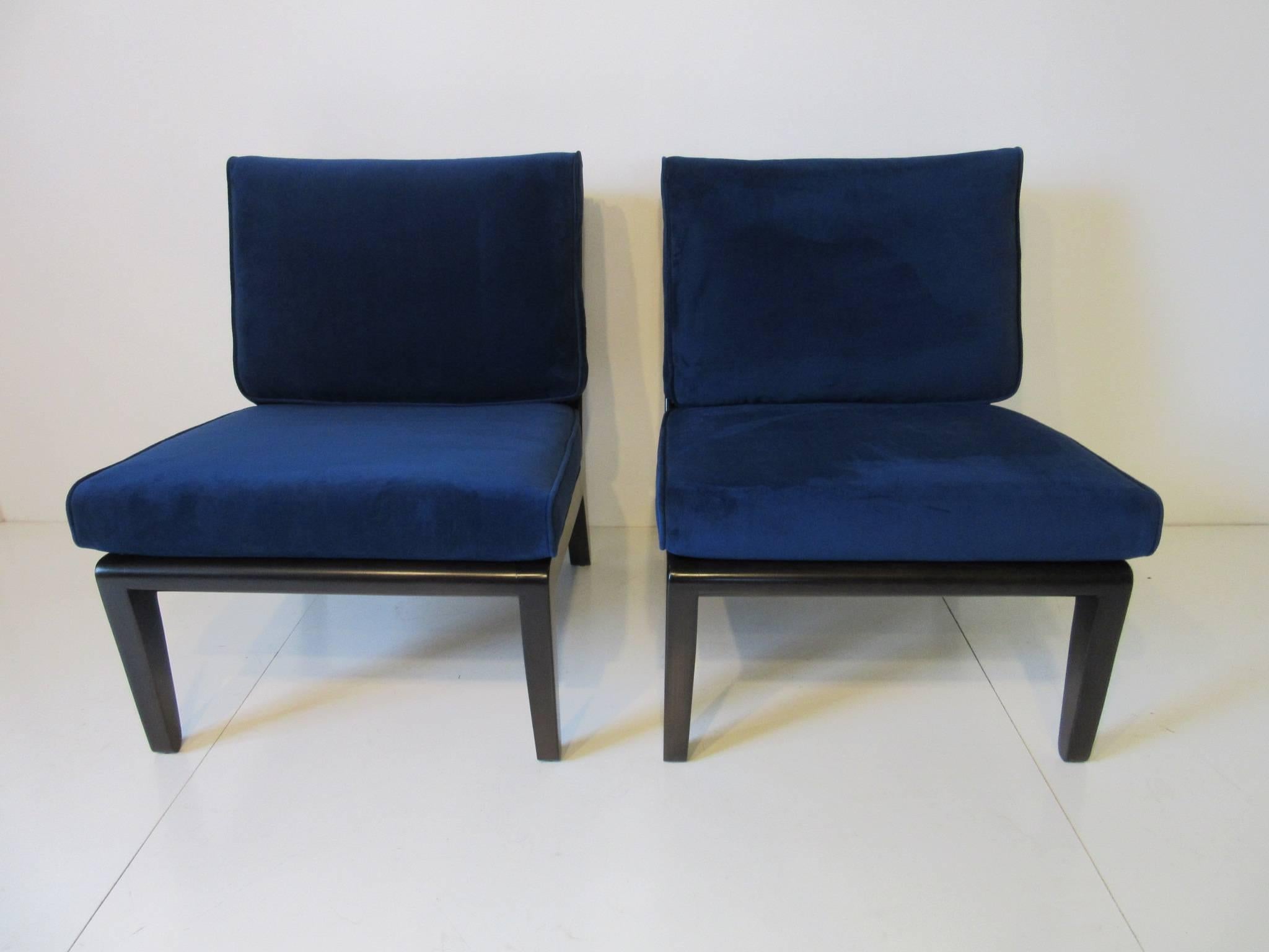 A pair of dark ebony finished slipper chairs with rich sapphire blue velvet upholstered cushions with rolled edges to accent the roll of the legs. Manufactured by Drexel and designed by Edward Wormley.