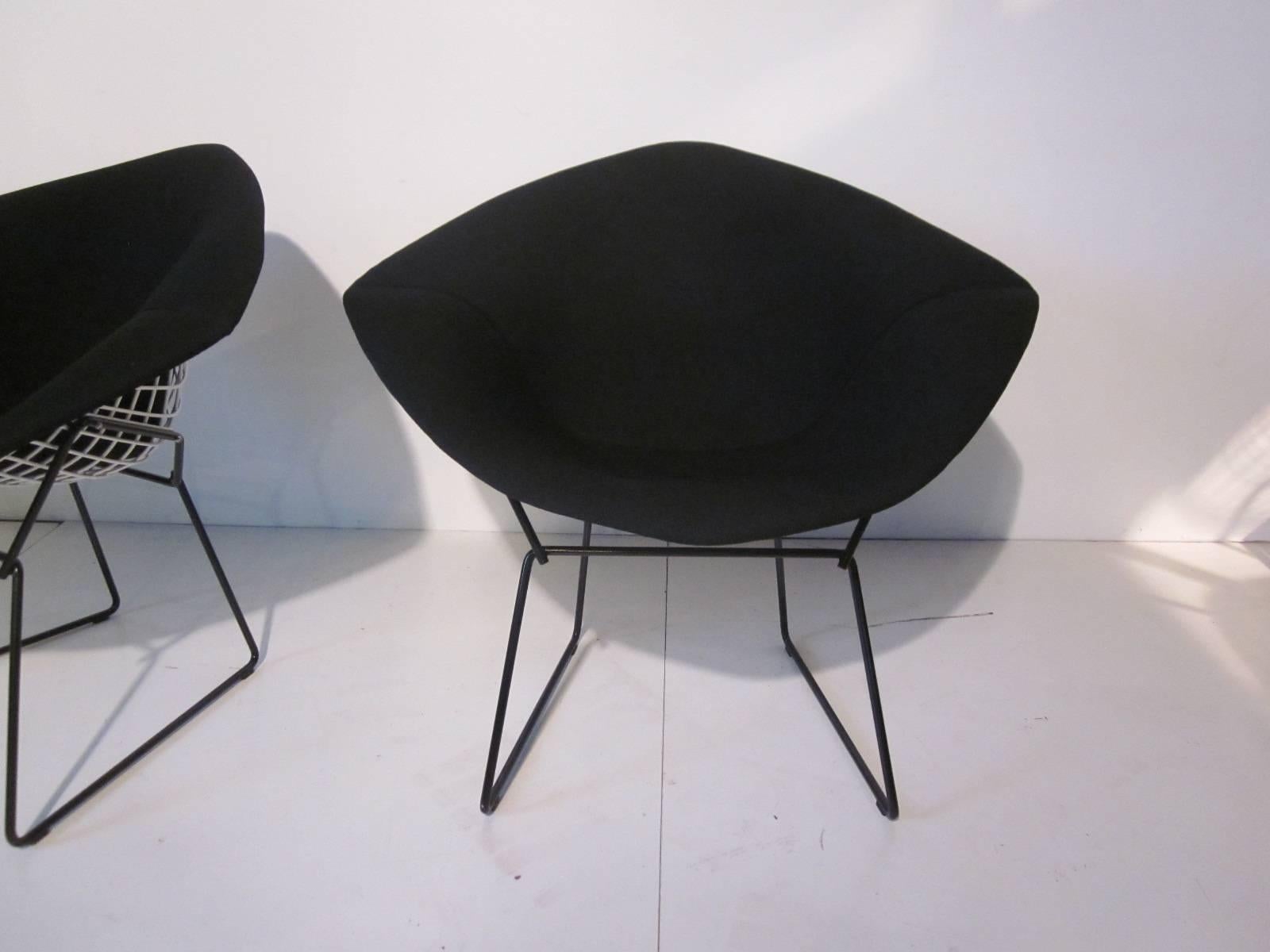 A pair of Bertoia small diamond chairs with white coated seat frame, black blended soft wool type covers sitting on black coated legs. A Classic design with a sculptural presence and comfortable to relax in. Retains the fabric tag from Knoll